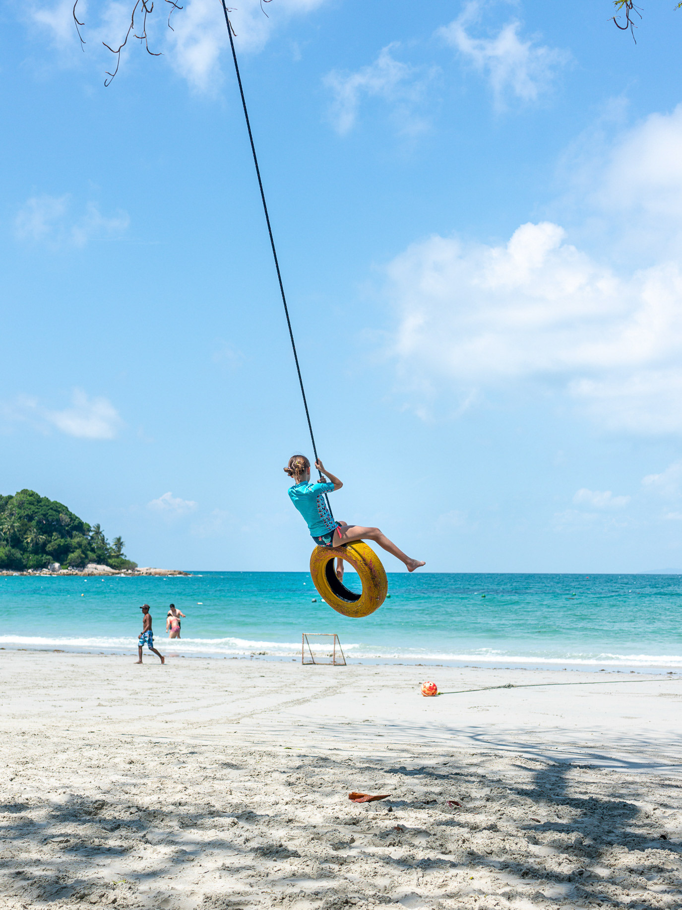 A child swinging from a tyre over a tropical beach in Bintan, Indonesia. Photograph by Alex Galmeanu.