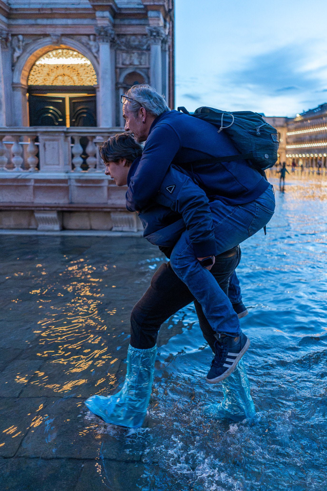One man carrying another through a flooded square in Venice, Italy. Photograph by Alex Galmeanu.