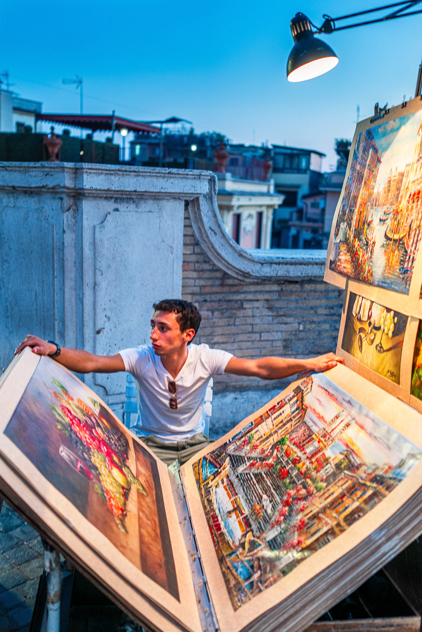 An art vendor unfolding a large city print on a Rome street in Italy. Photograph by Alex Galmeanu.