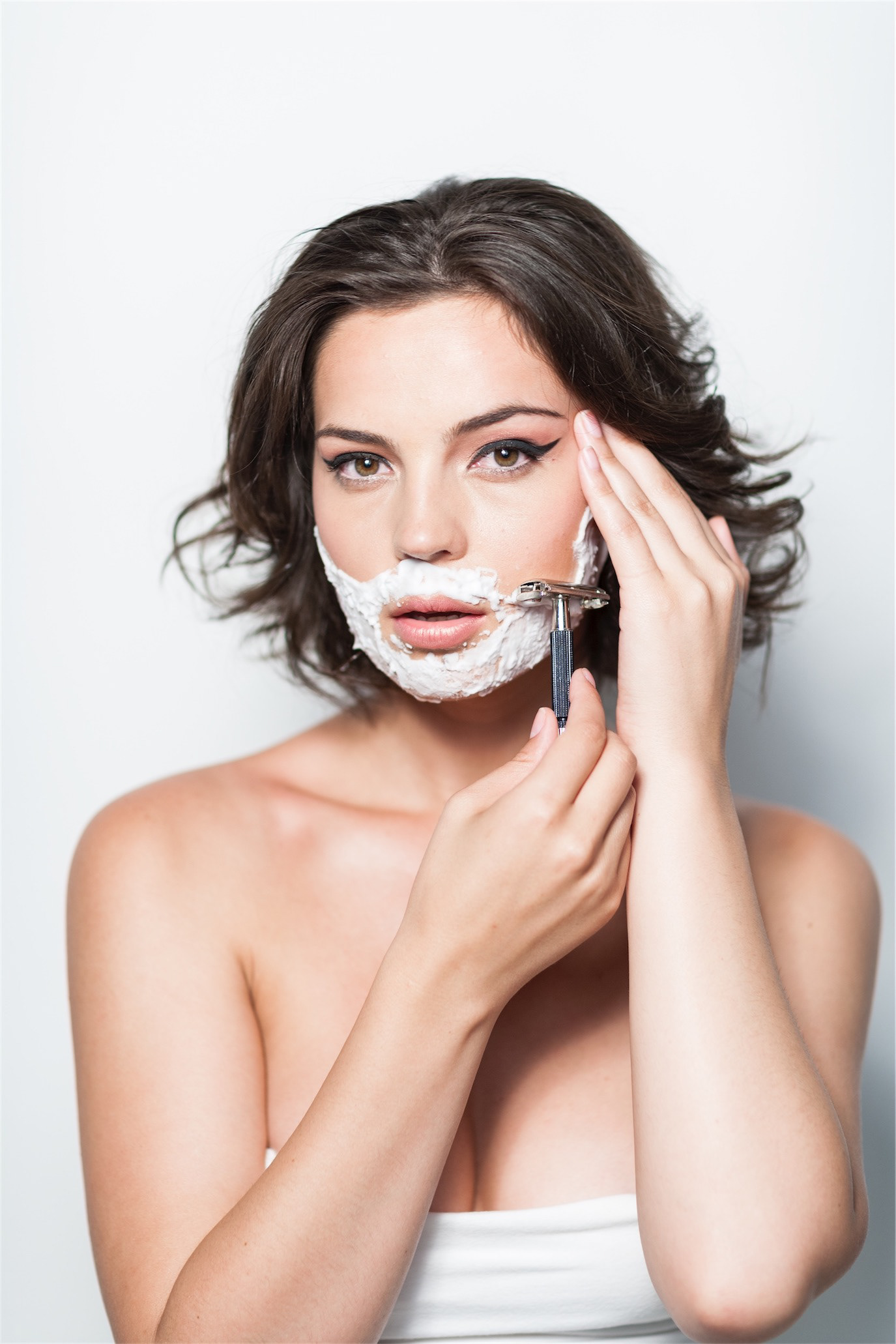 Maria Dinulescu wearing a shaving-foam beard and holding a razor, photographed by Alex Gâlmeanu.