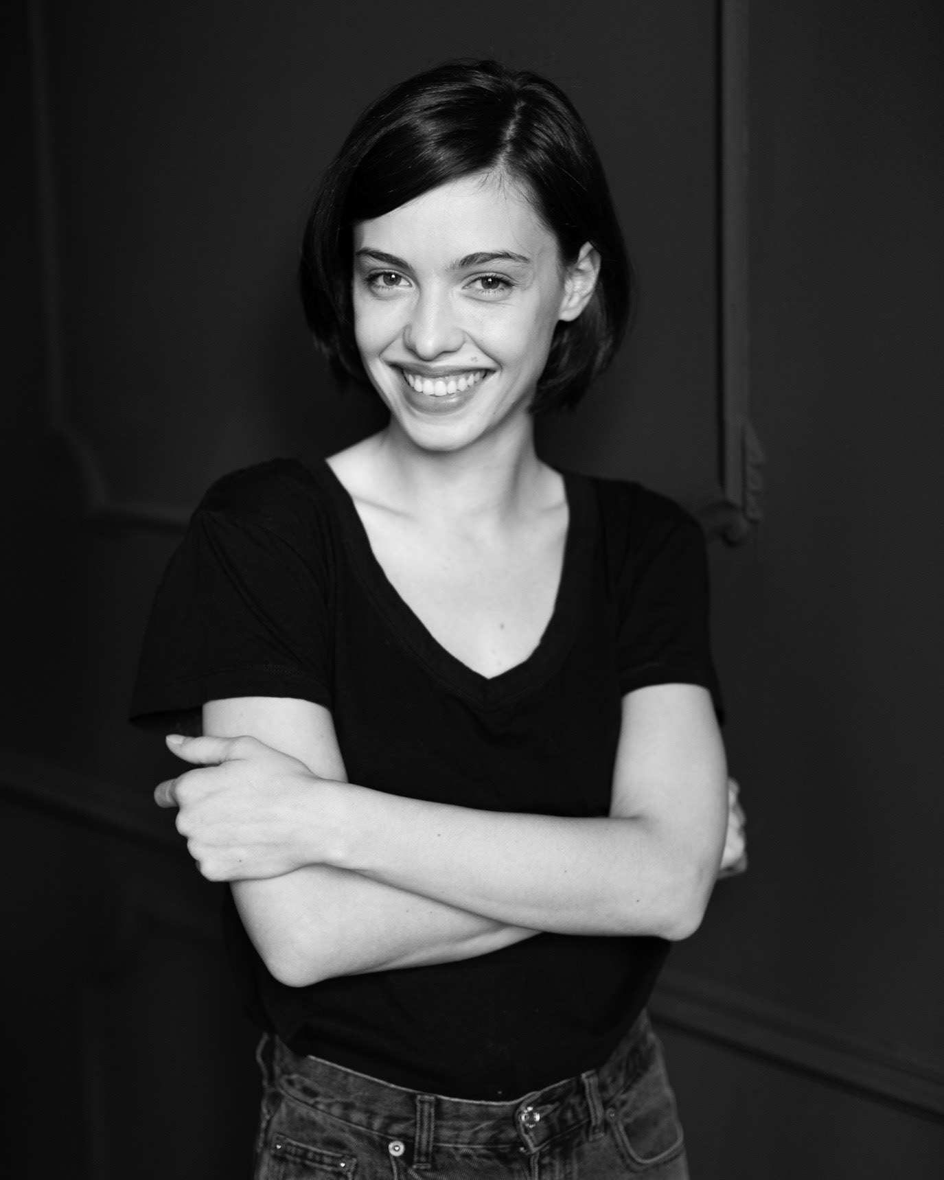 Black-and-white portrait of actor Ioana Bugarin smiling with her arms crossed, photographed by Alex Gâlmeanu.