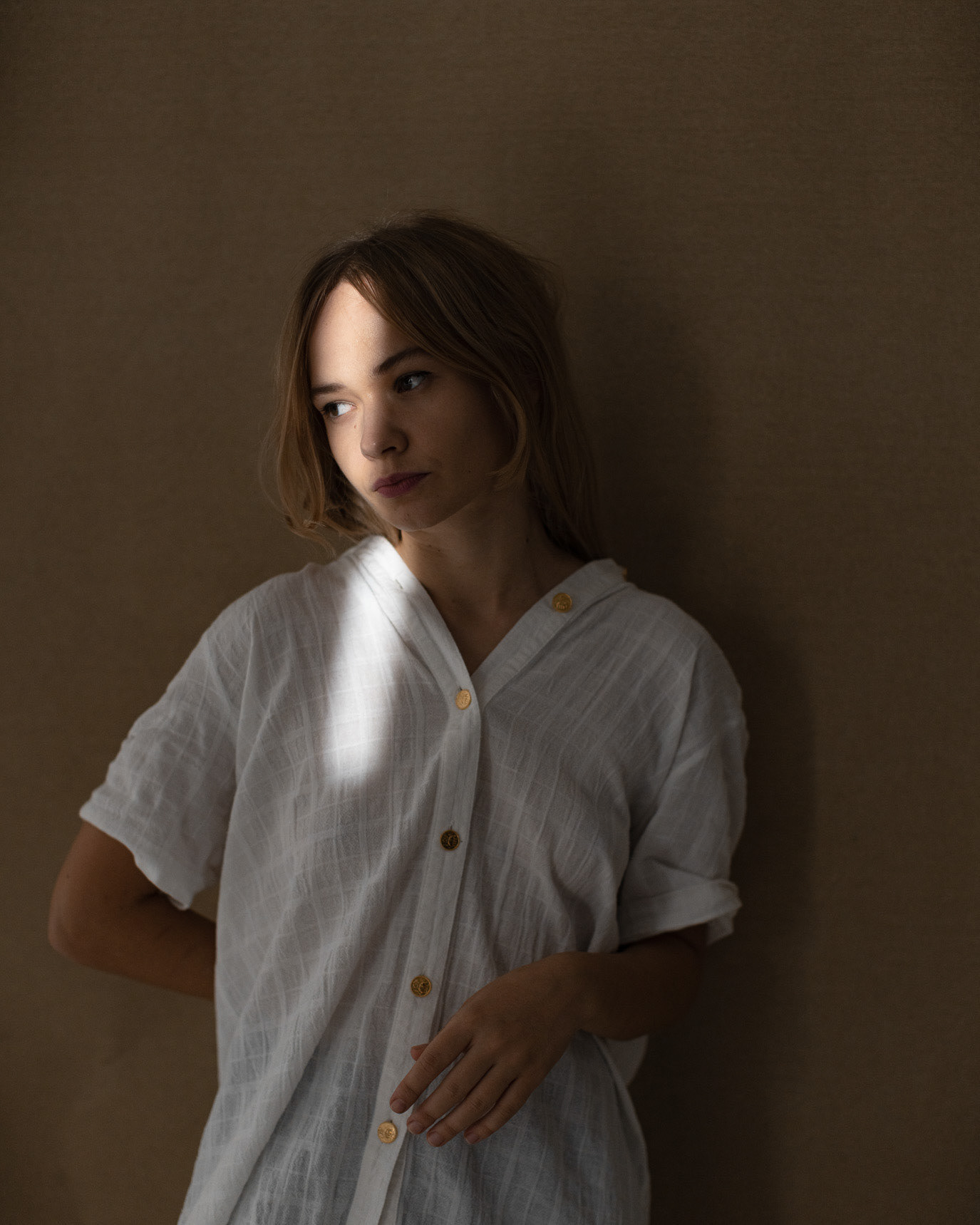 Portrait of actor Silvana Mihai in a white dress against a warm-toned studio background, photographed by Alex Gâlmeanu.