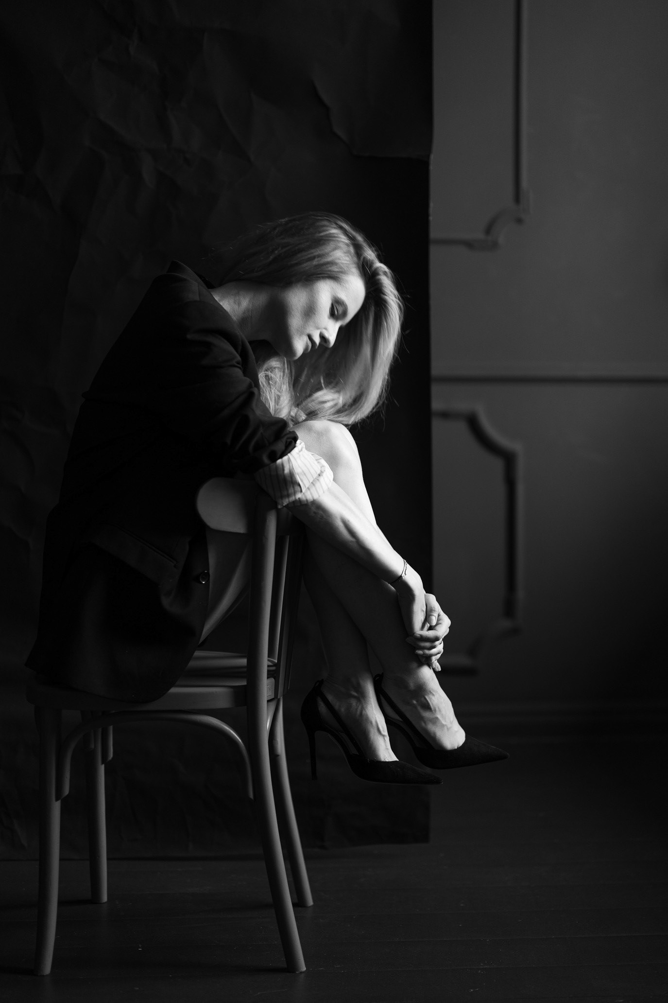 Black-and-white portrait of model and entrepreneur Silvia Giurca curled over a chair, photographed by Alex Gâlmeanu.