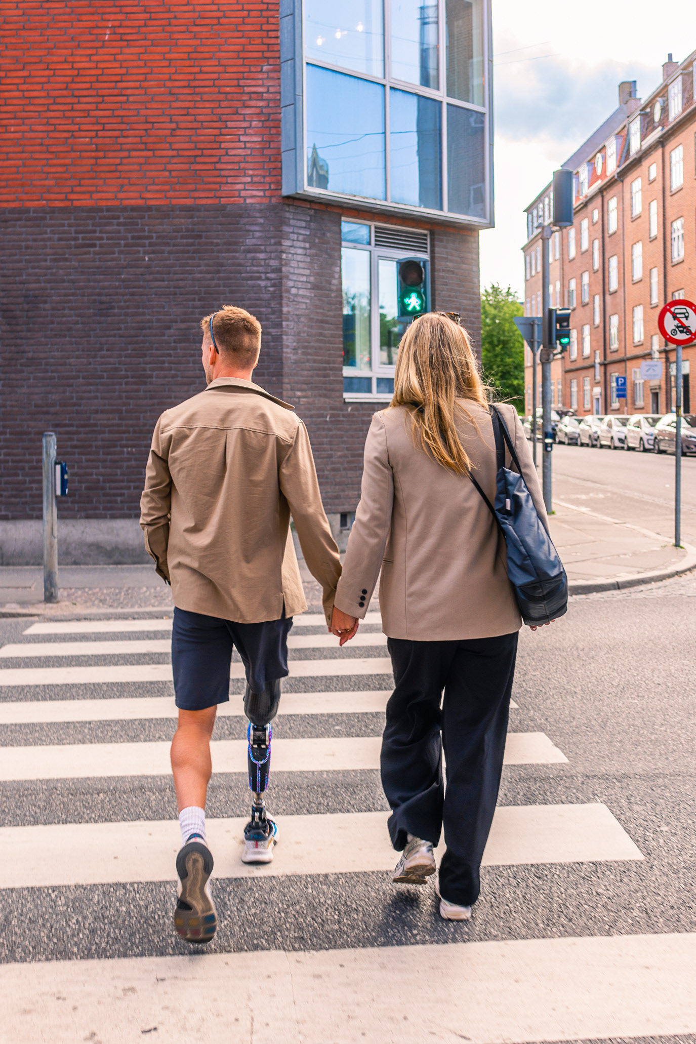 A man with prosthetic legs walking hand in hand across a street in Aarhus, Denmark. Photograph by Alex Galmeanu.
