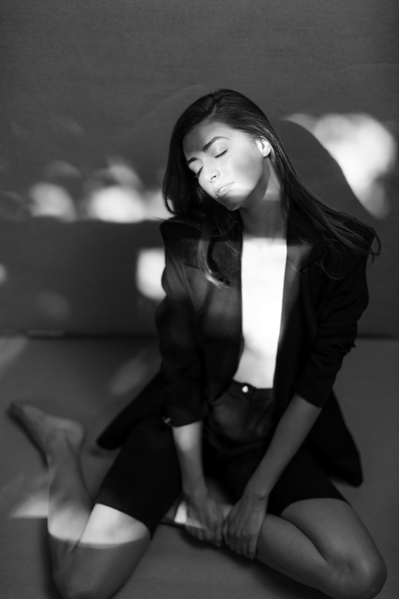 Black-and-white portrait of model Ana Stefanescu kneeling in a pool of studio light, photographed by Alex Gâlmeanu.