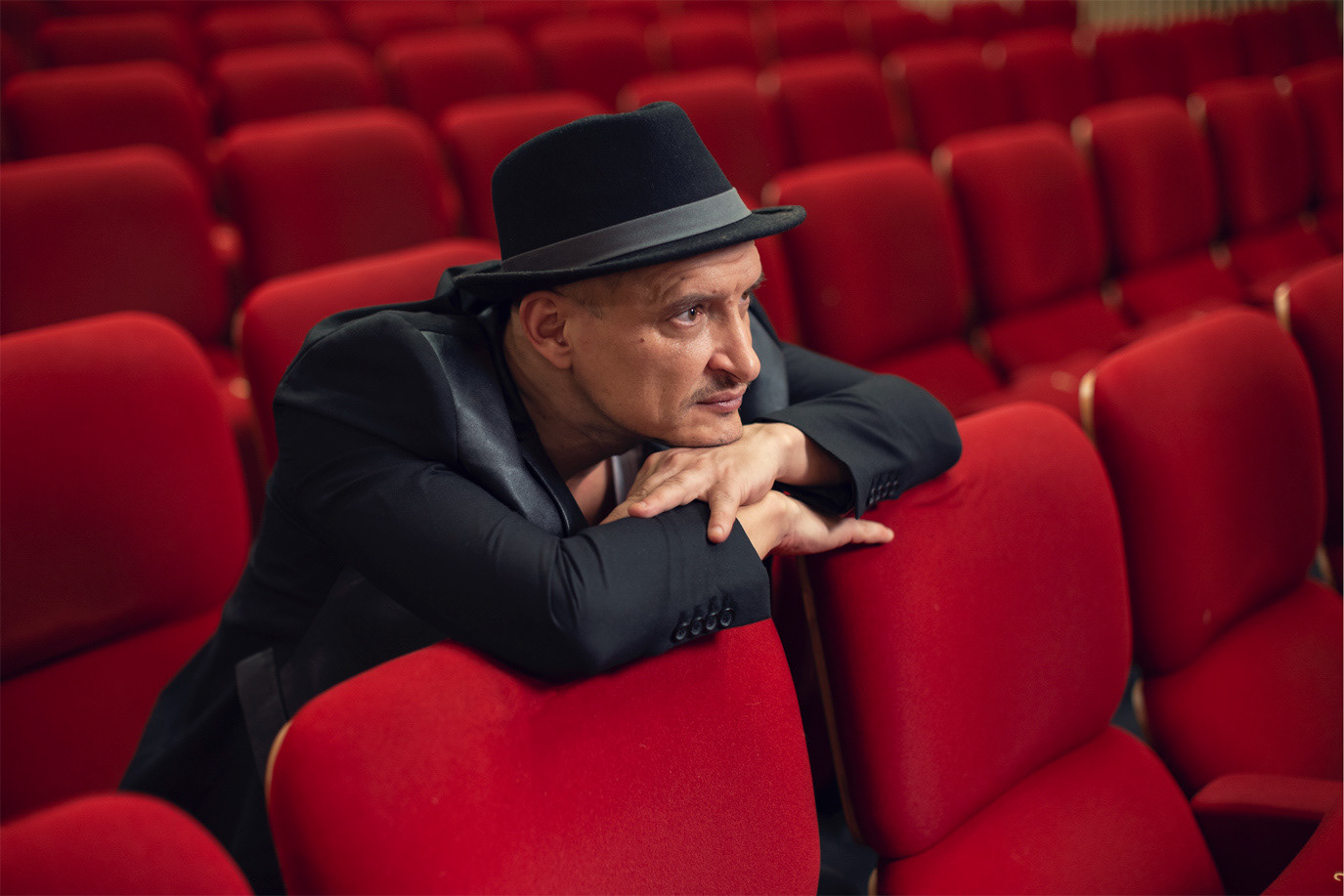 Mihai Chirilov leaning across the red seats of an empty theatre, photographed by Alex Gâlmeanu.