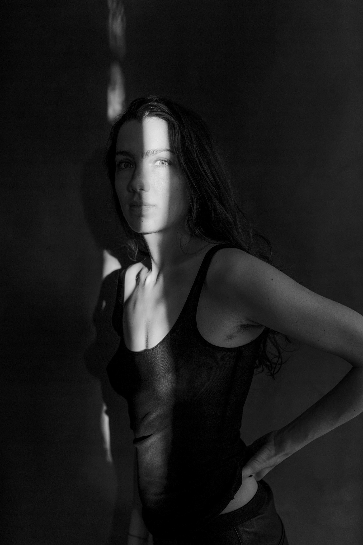 Black-and-white portrait of artist Ioana Sisea partly crossed by a narrow beam of light, photographed by Alex Gâlmeanu.