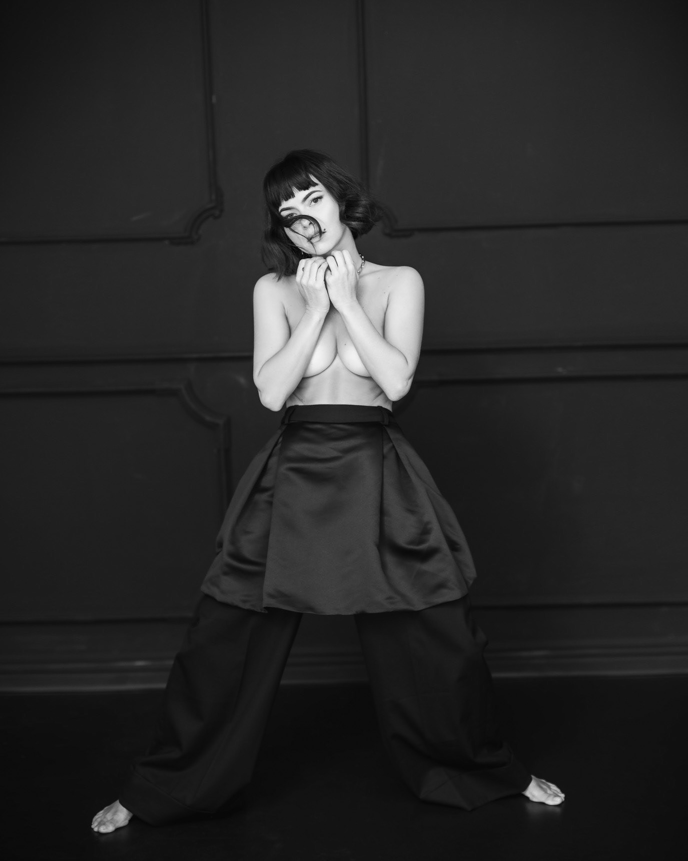 Black-and-white full-length portrait of singer INNA smiling with her hands beneath her chin, photographed by Alex Gâlmeanu.