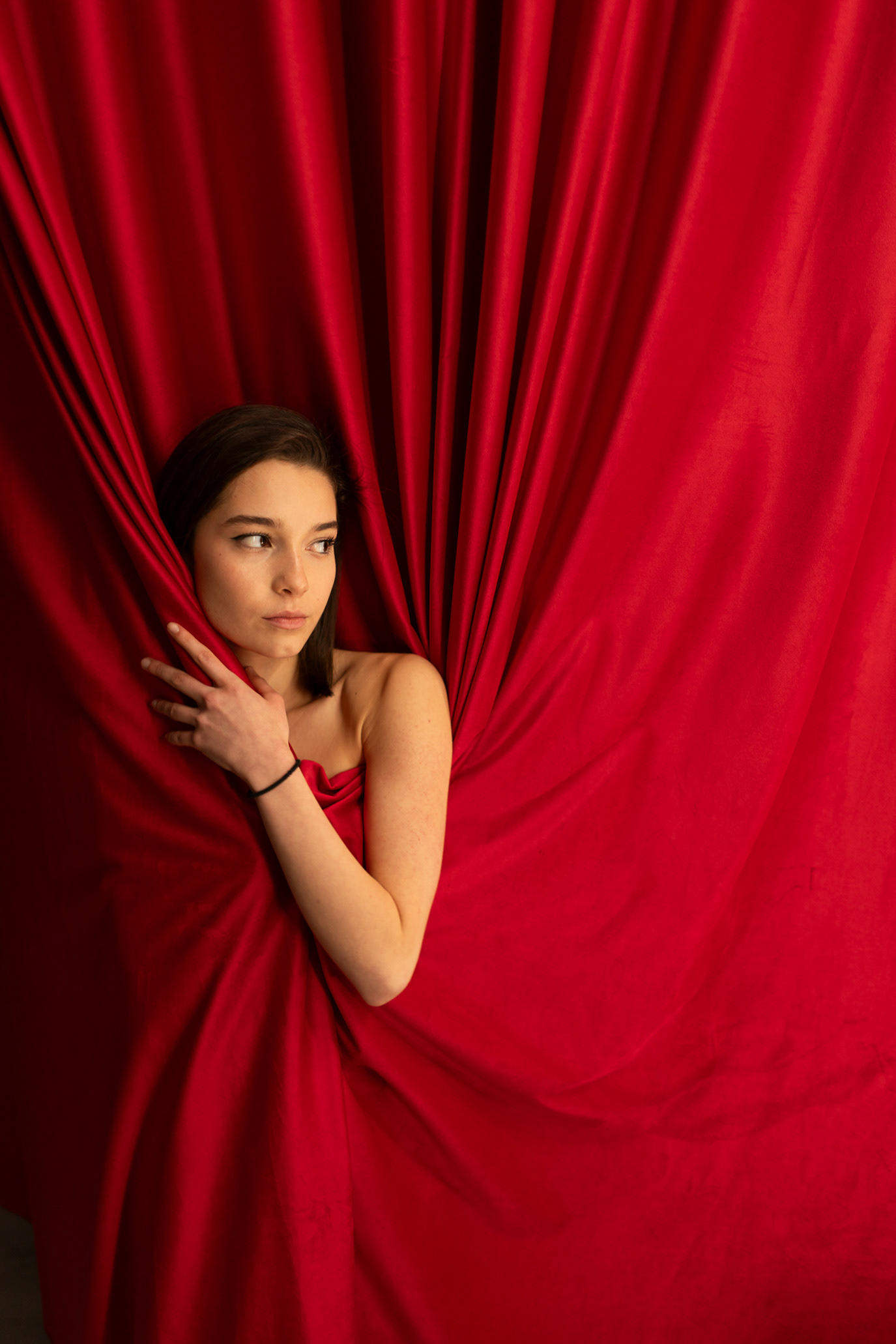 Anaïs Agi-Ali emerging from folds of vivid red fabric, photographed by Alex Gâlmeanu.