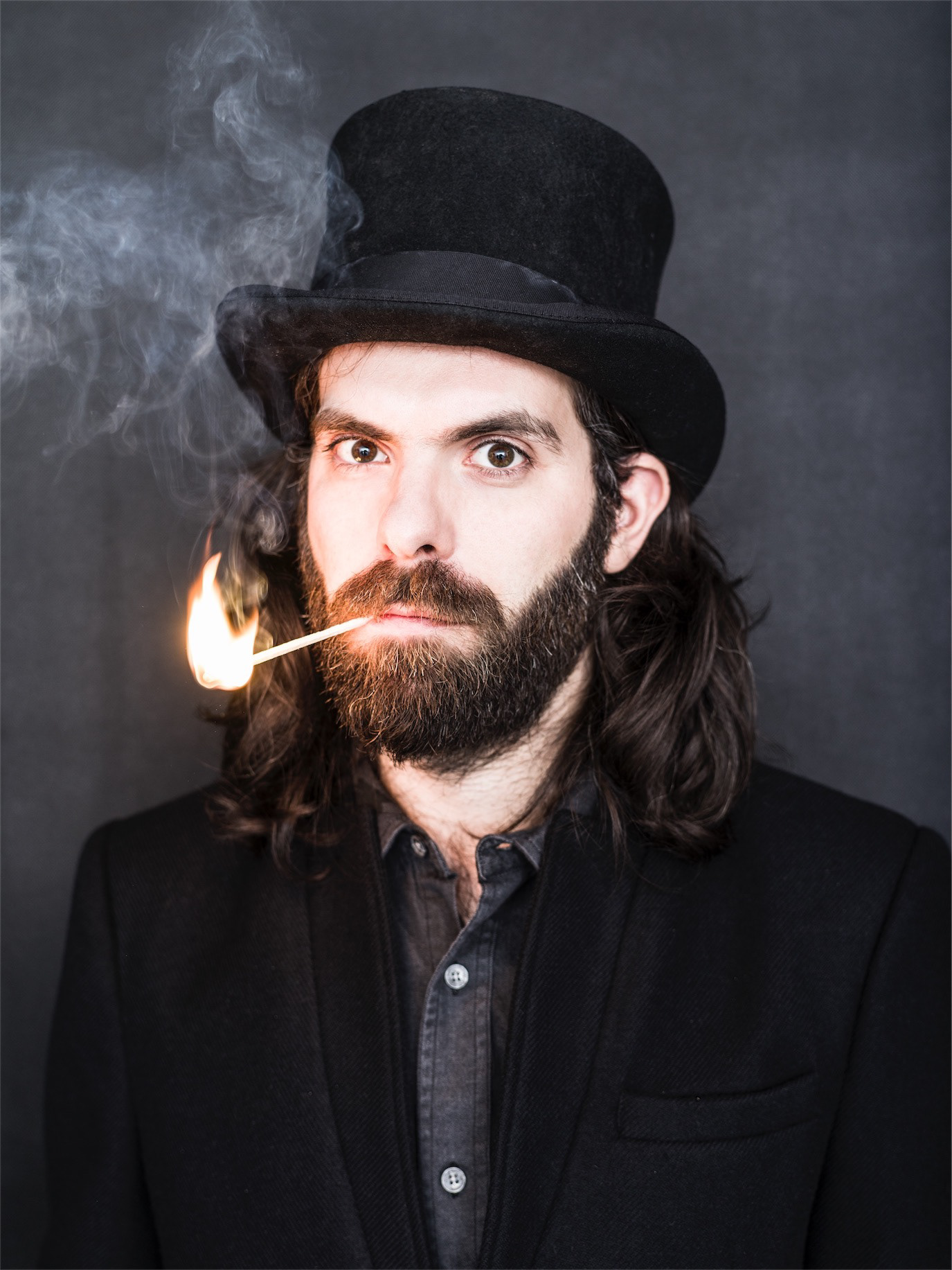 Andrei Proca wearing a top hat with a burning match between his lips, photographed by Alex Gâlmeanu.