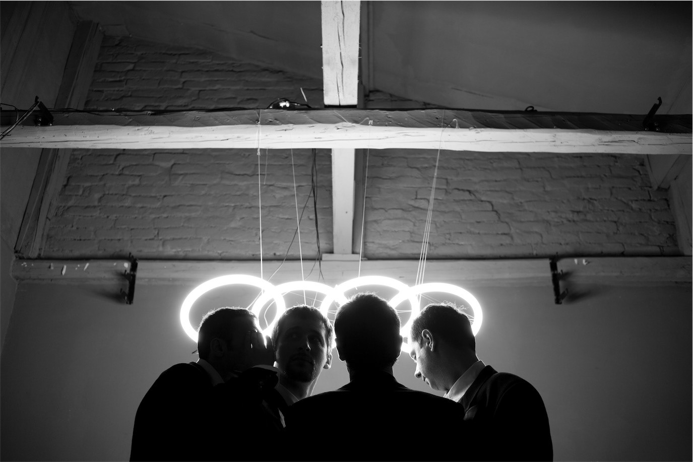 Silhouetted group beneath large illuminated Audi rings, photographed by Alex Gâlmeanu.