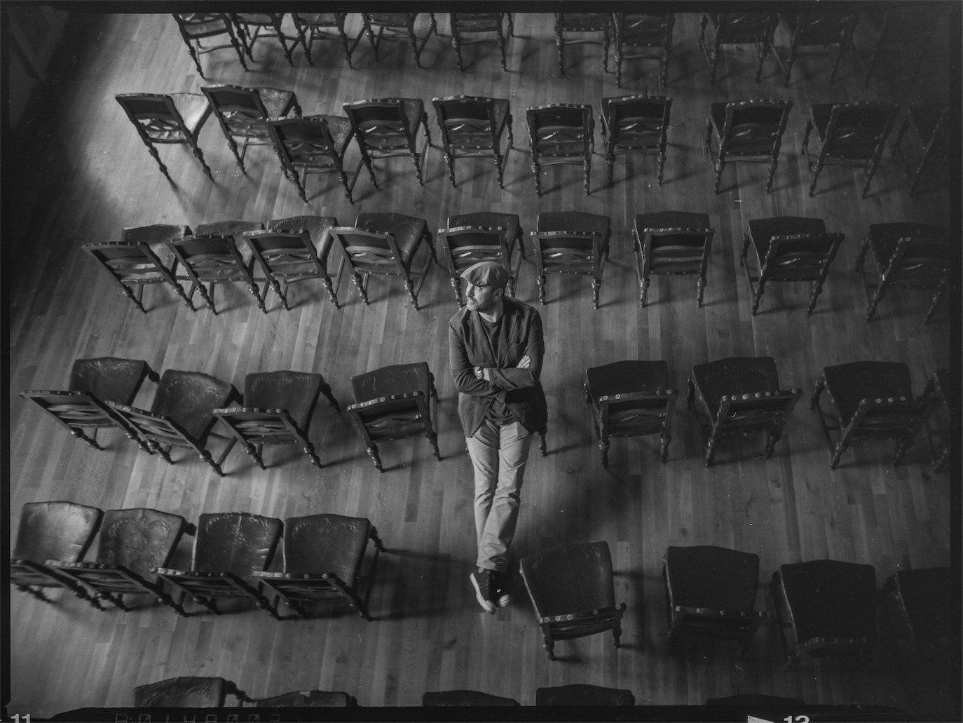 Cătălin Ștefănescu seen from above among staggered rows of folding chairs, photographed by Alex Gâlmeanu.