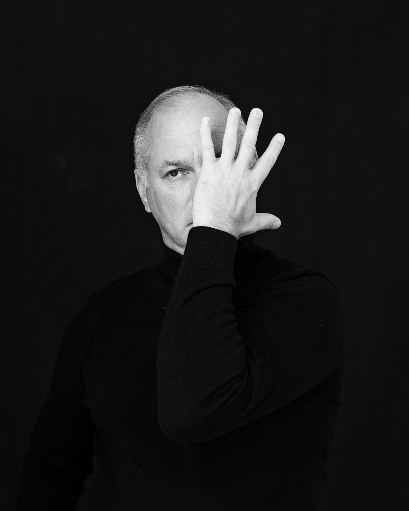 Black-and-white portrait of actor Vlad Ivanov covering part of his face with one hand, photographed by Alex Gâlmeanu.