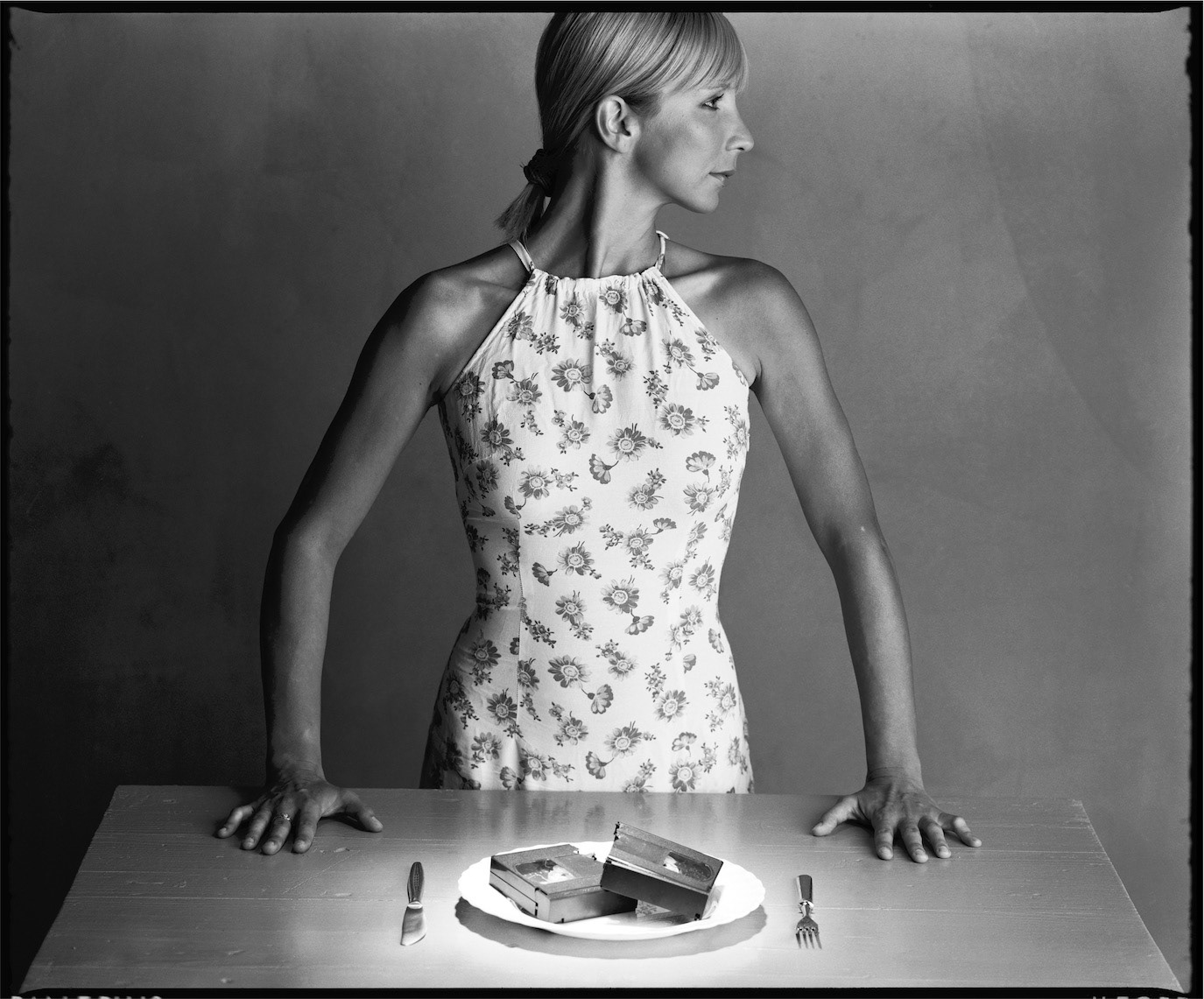 Andreea Păduraru standing behind a table set with VHS cassettes on a plate, photographed by Alex Gâlmeanu.