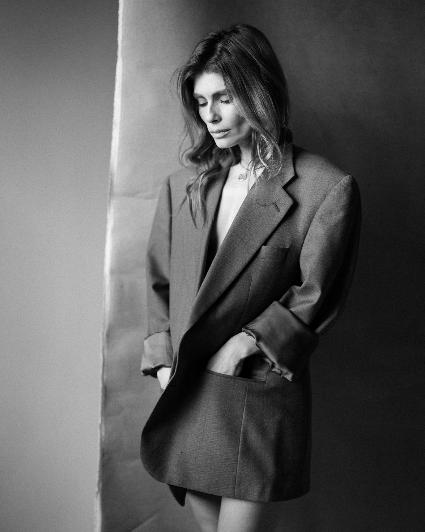 Black-and-white portrait of content creator Sanziana Negru in an oversized blazer, looking down in side light, photographed by Alex Gâlmeanu.