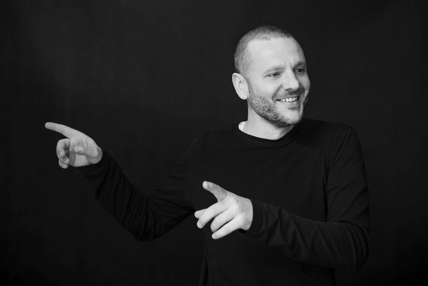 Bogdan Dumitrache laughing and pointing in a black-and-white portrait, photographed by Alex Gâlmeanu.