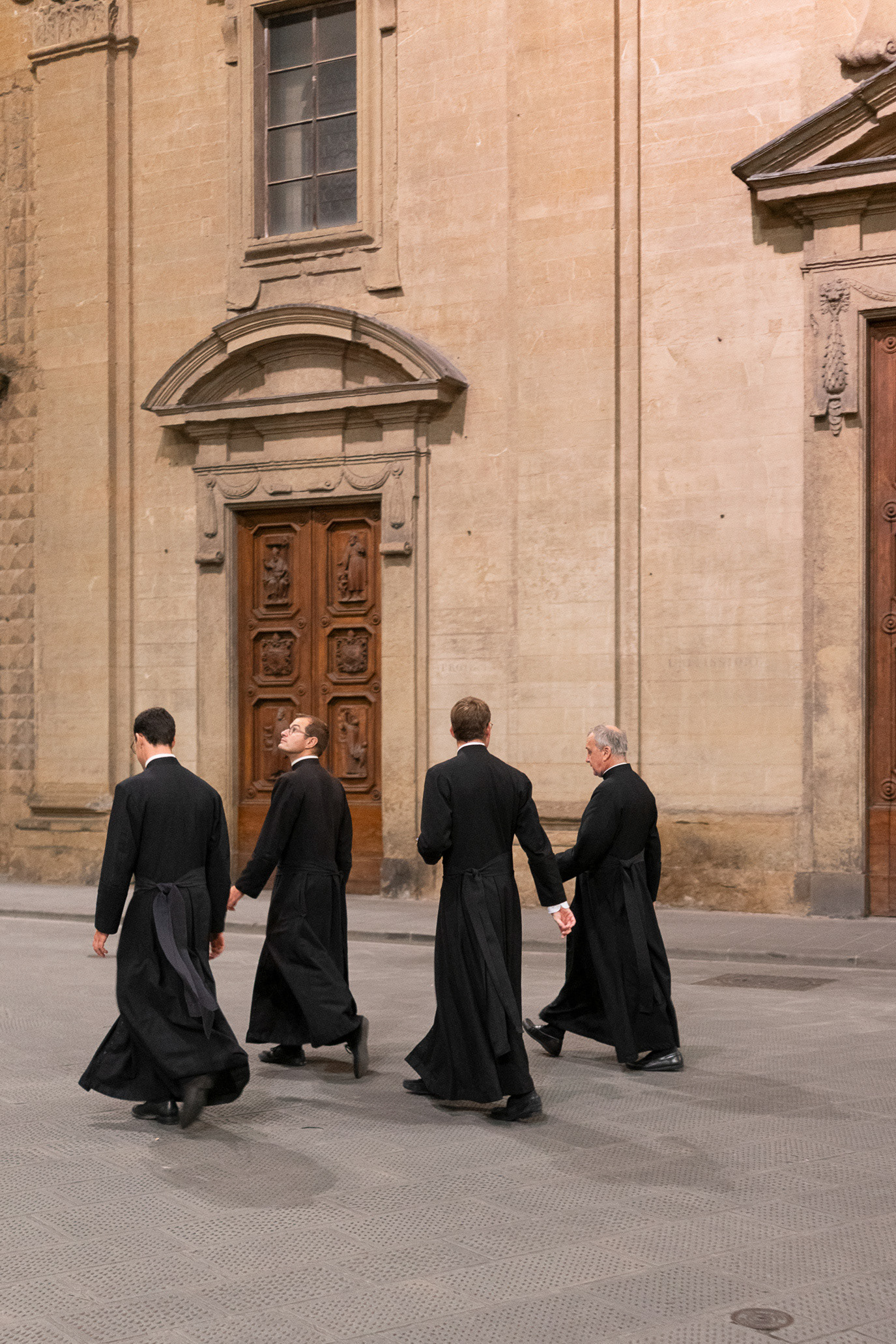 Four members of the clergy walking past a church in Florence, Italy. Photograph by Alex Galmeanu.