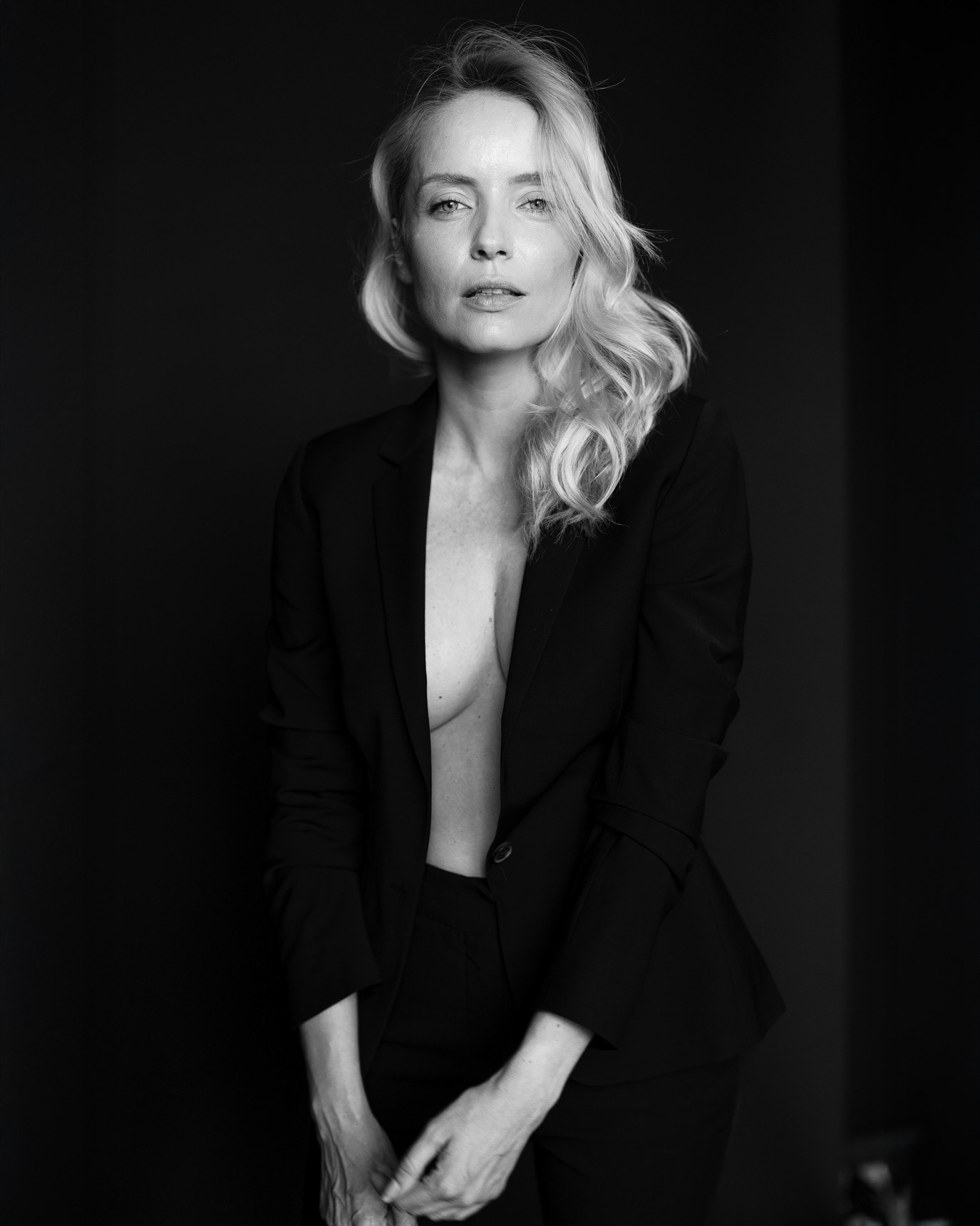 Black-and-white portrait of model Cristiana Grasu seated in an open dark blazer, photographed by Alex Gâlmeanu.
