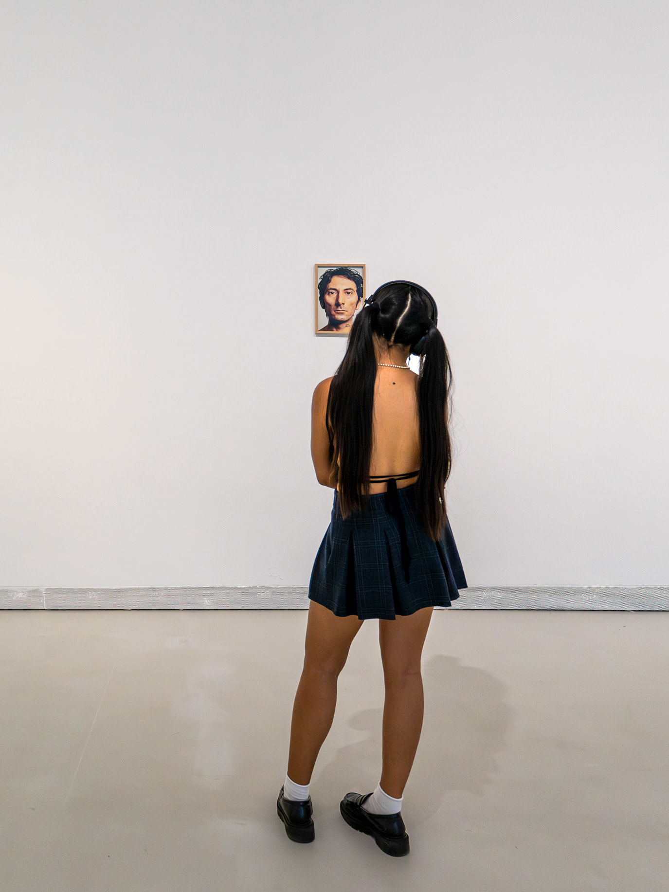 A gallery visitor visually aligned with a small painted portrait in Rome, Italy. Photograph by Alex Galmeanu.