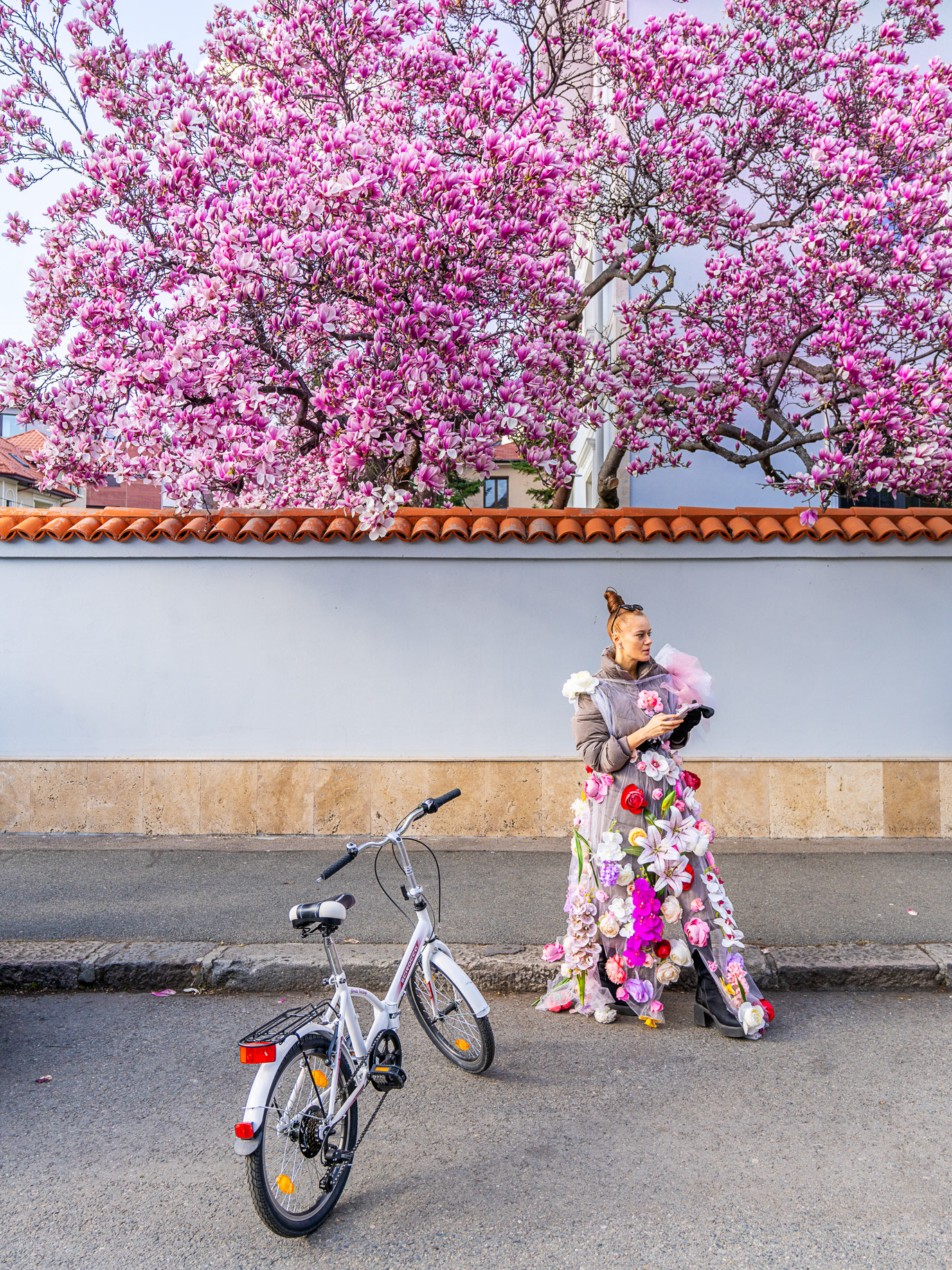 A flower-covered woman beside a bicycle beneath a blooming magnolia tree in Bucharest, Romania. Photograph by Alex Galmeanu.