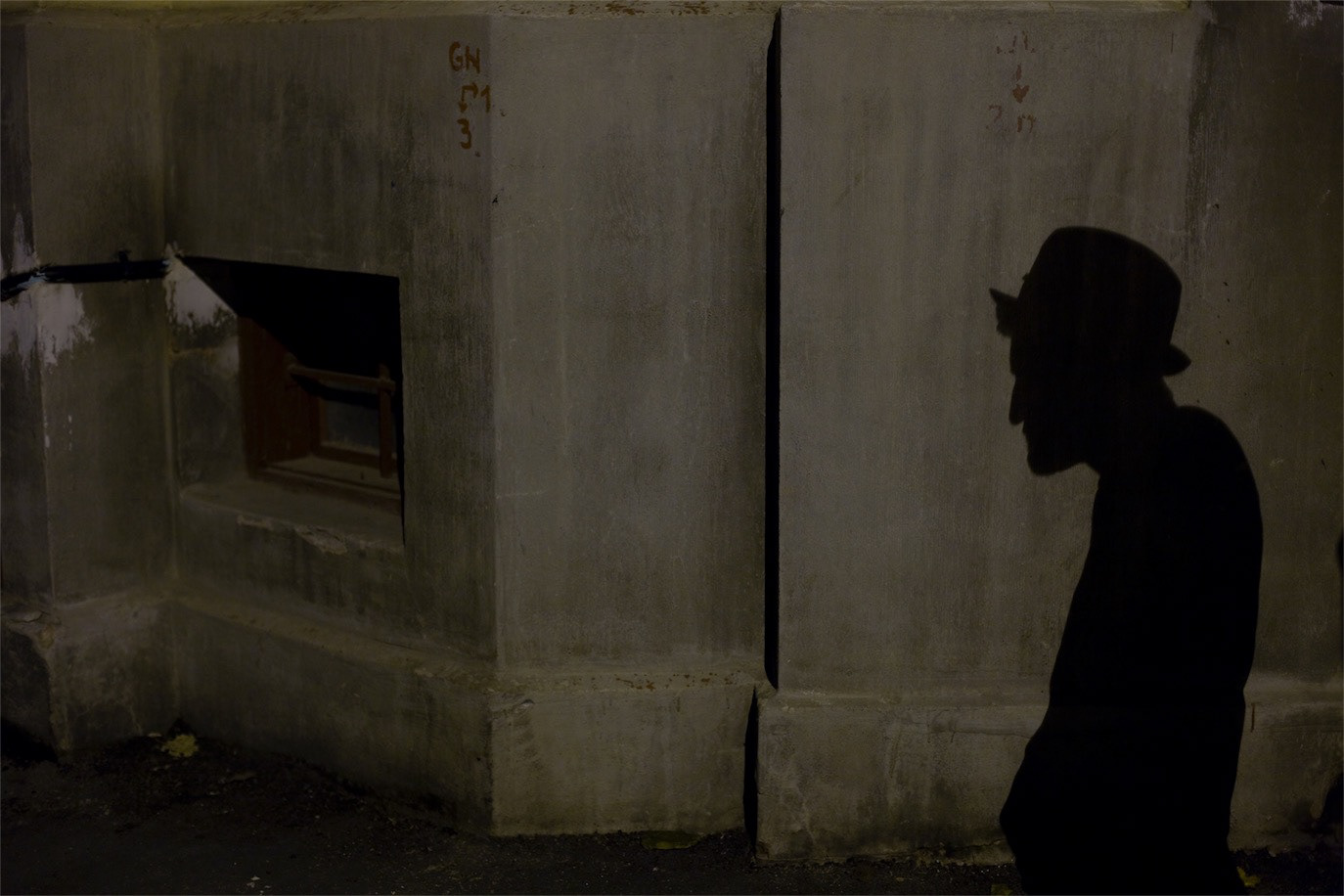 Smiley represented by a hat-wearing silhouette cast on a concrete wall, photographed by Alex Gâlmeanu.