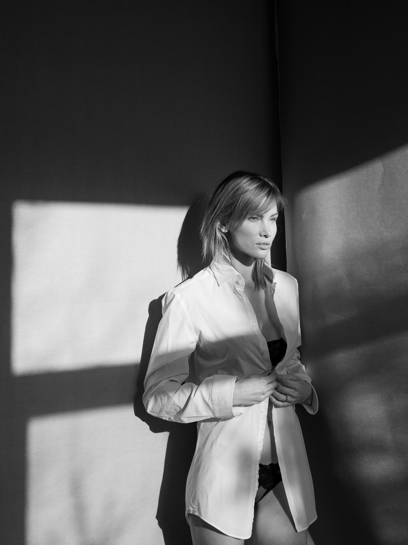 Black-and-white portrait of model Gabriela Iliescu in a white suit and hard studio light, photographed by Alex Gâlmeanu.