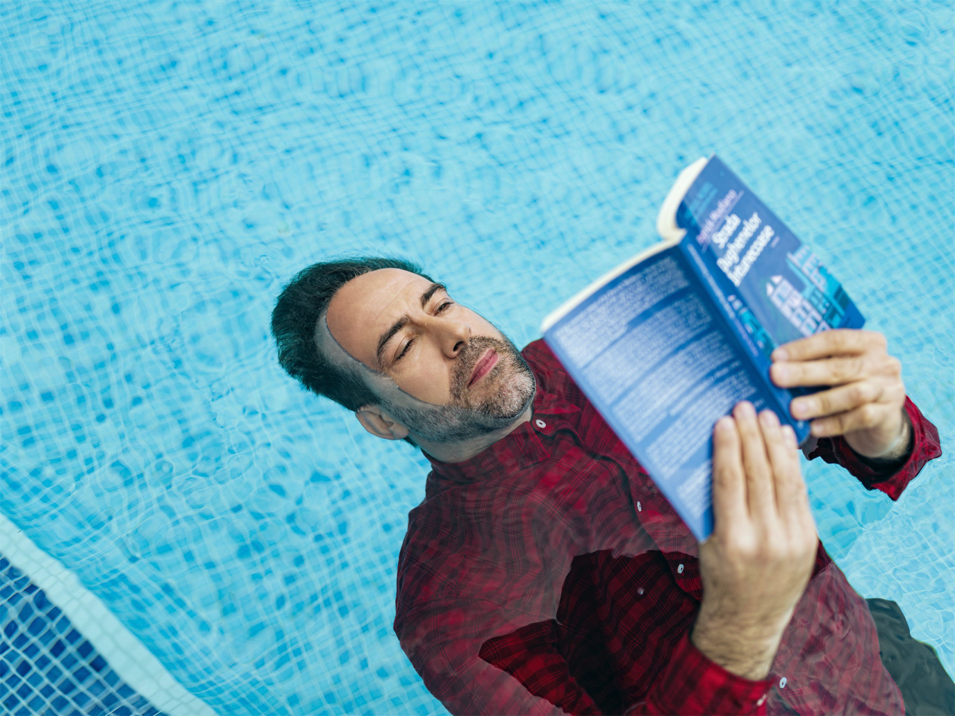 Șerban Pavlu lying in an empty swimming pool and reading a book, photographed by Alex Gâlmeanu.