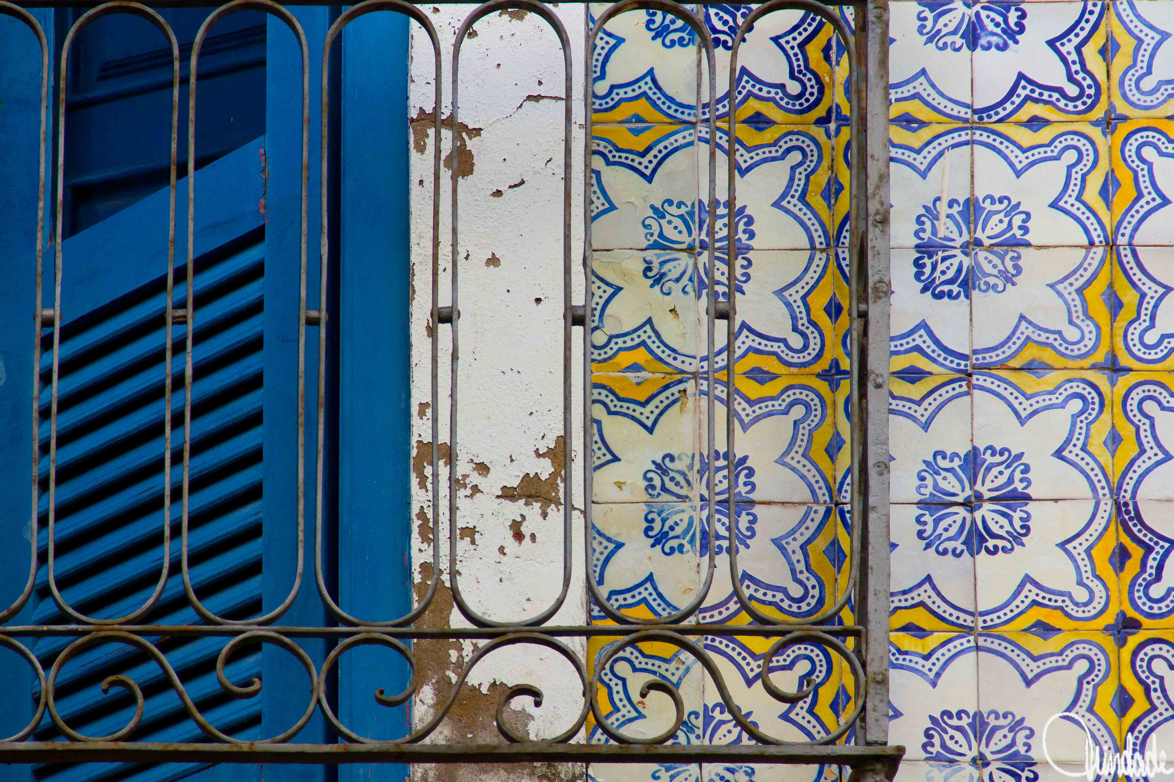 Detalhe de fachada histórica em São Luís do Maranhão, com janela azul de madeira, azulejos coloniais em azul e amarelo e grades de ferro trabalhadas.