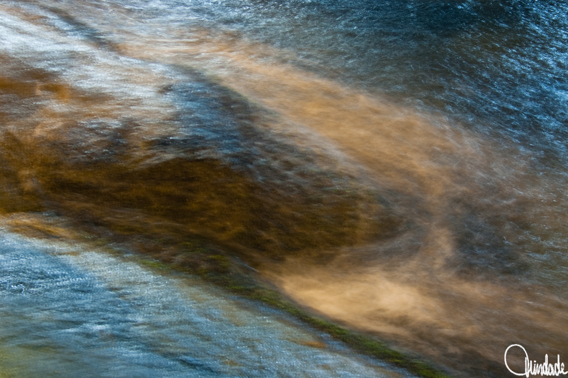 Close da superfície do mar em Copacabana, com reflexos de luzes urbanas criando padrões abstratos em tons de azul e marrom. Movimento da água suavizado por longa exposição, formando textura fluida e pictórica.