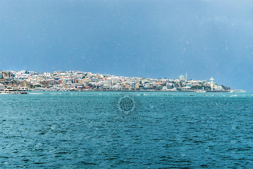 Holding the City (Istanbul, Turkey) - Snowfall along the Bosphorus is rare, and when it arrives it briefly transforms the city. Here, a momentary break in the clouds allows sunlight to illuminate the snow-covered Asian shore as the storm continues. ($350)