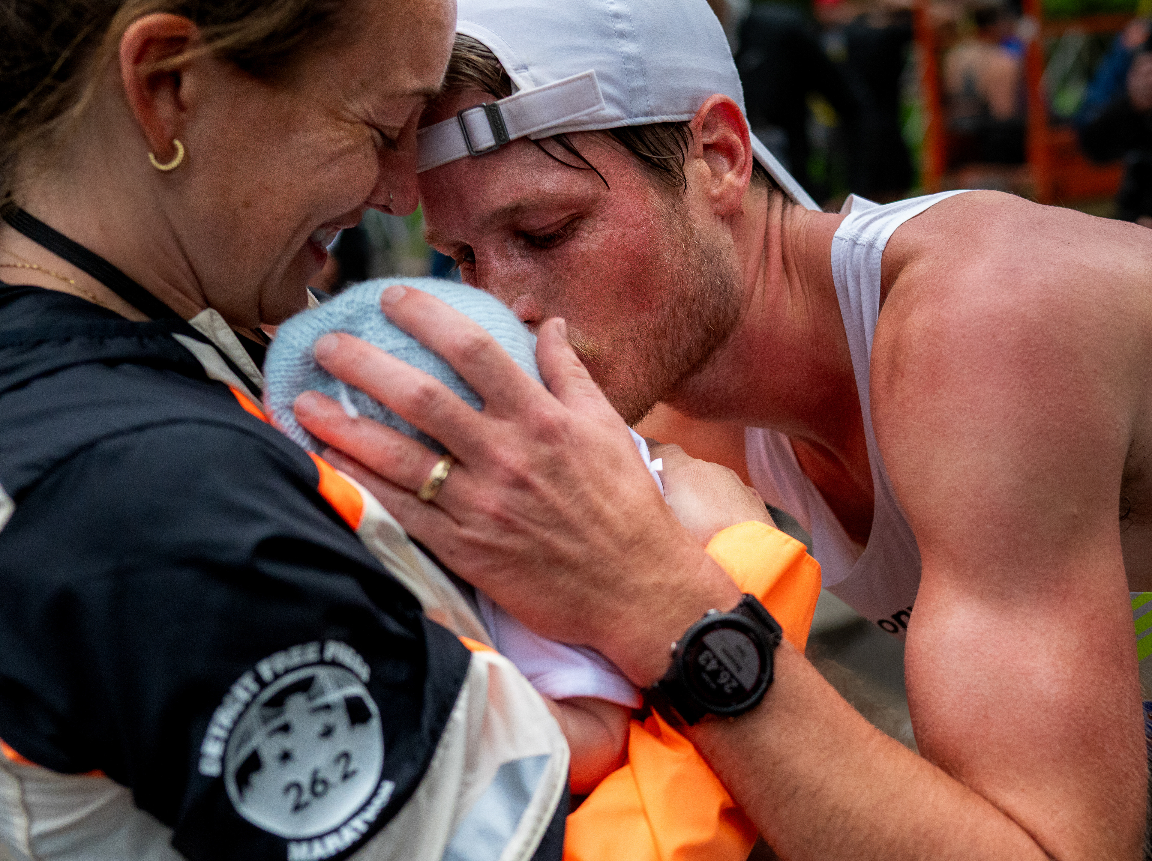 Andy Bowman (R) wins the male marathon race and embraces his wife Sydney Devore-Bowman (L) and their 3-week-old son Liam during the 48th annual Detroit Free Press Marathon presented by MSU Federal Credit Union in Detroit, Michigan, on Sunday, Oct. 19, 2025.