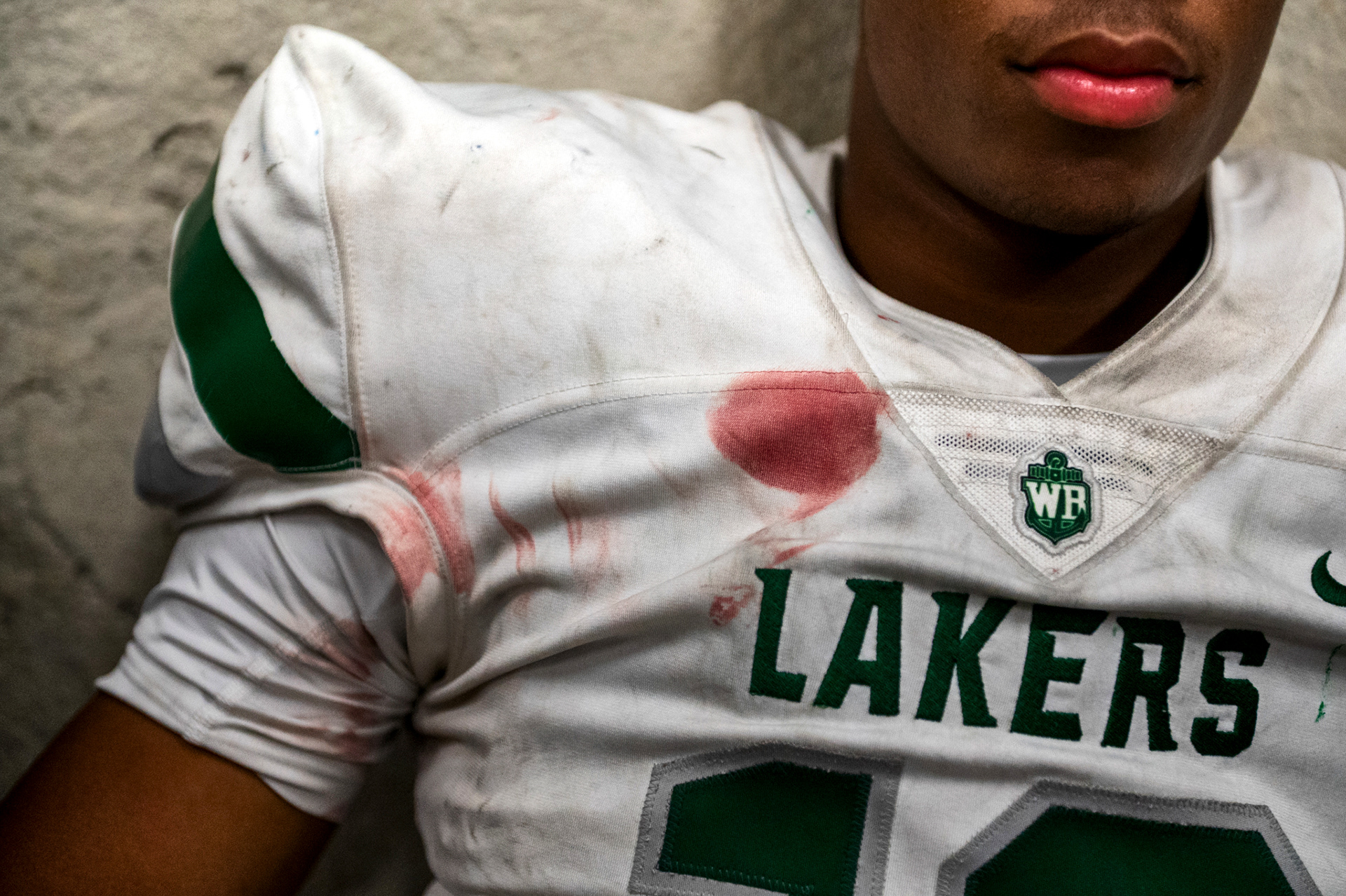 Junior defensive back Will Espy (12) of West Bloomfield High School sits in the locker room at halftime, his jersey splattered with blood, during a game against the Clarkston Wolves at West Bloomfield High School in West Bloomfield, Mich., on Friday, Sept. 27, 2024. “It’s not pretty, but this is what Friday nights are about - giving everything you have for the guy next to you,” Espy said.