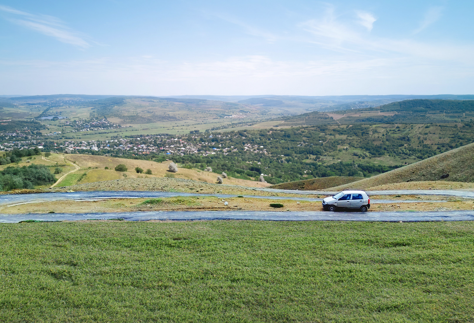 Replace the dry, patchy ground in the foreground with a vibrant, lush green grass lawn stretching across the bottom of the image.