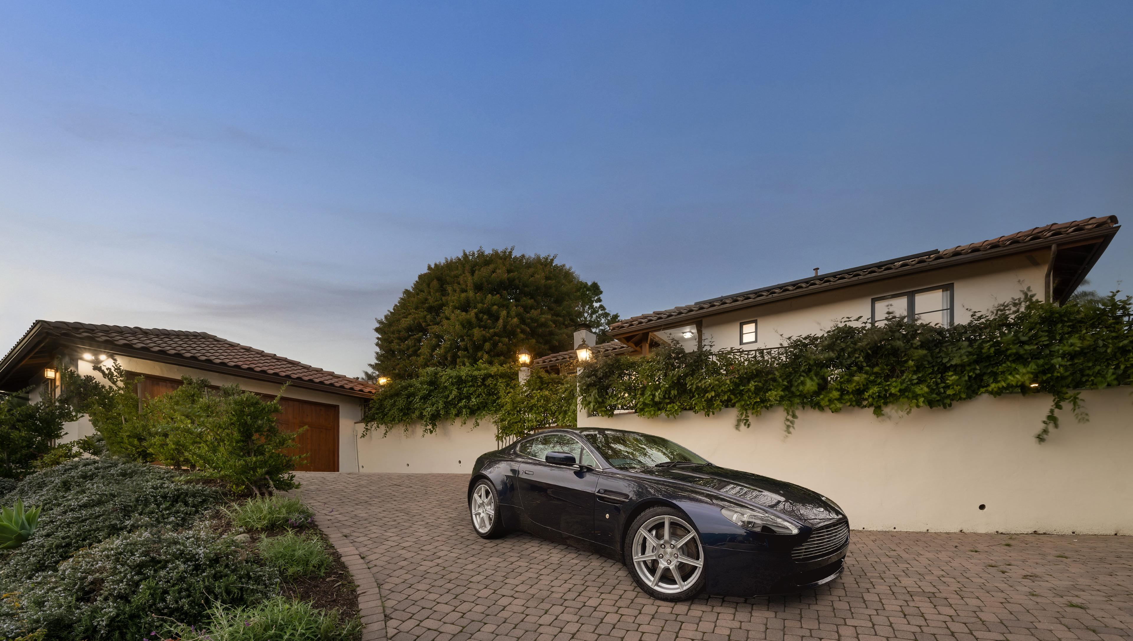 Add a dark blue sports car parked on the paved driveway.