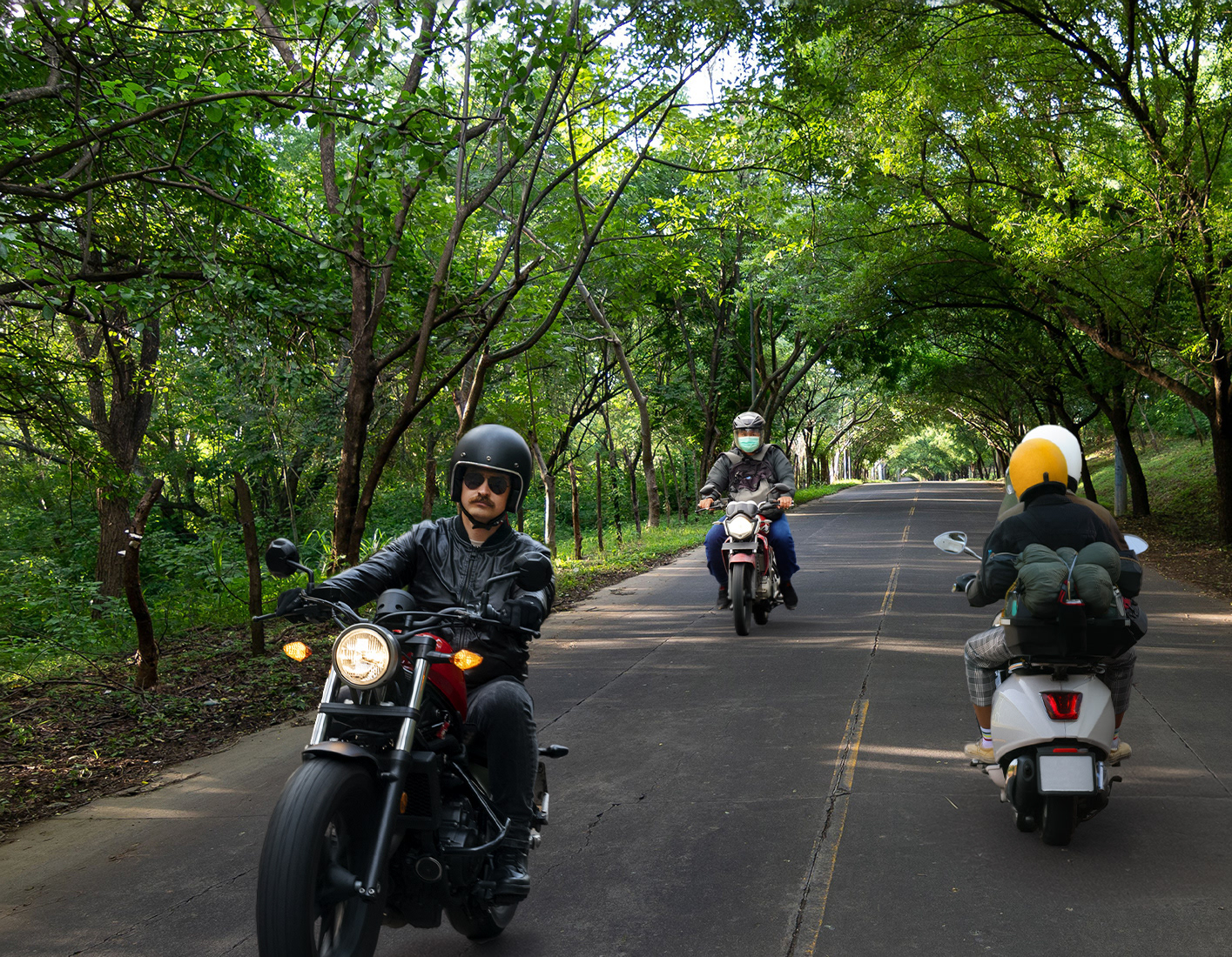 Add another motorcyclist riding down the center lane in the background wearing a helmet and mask.