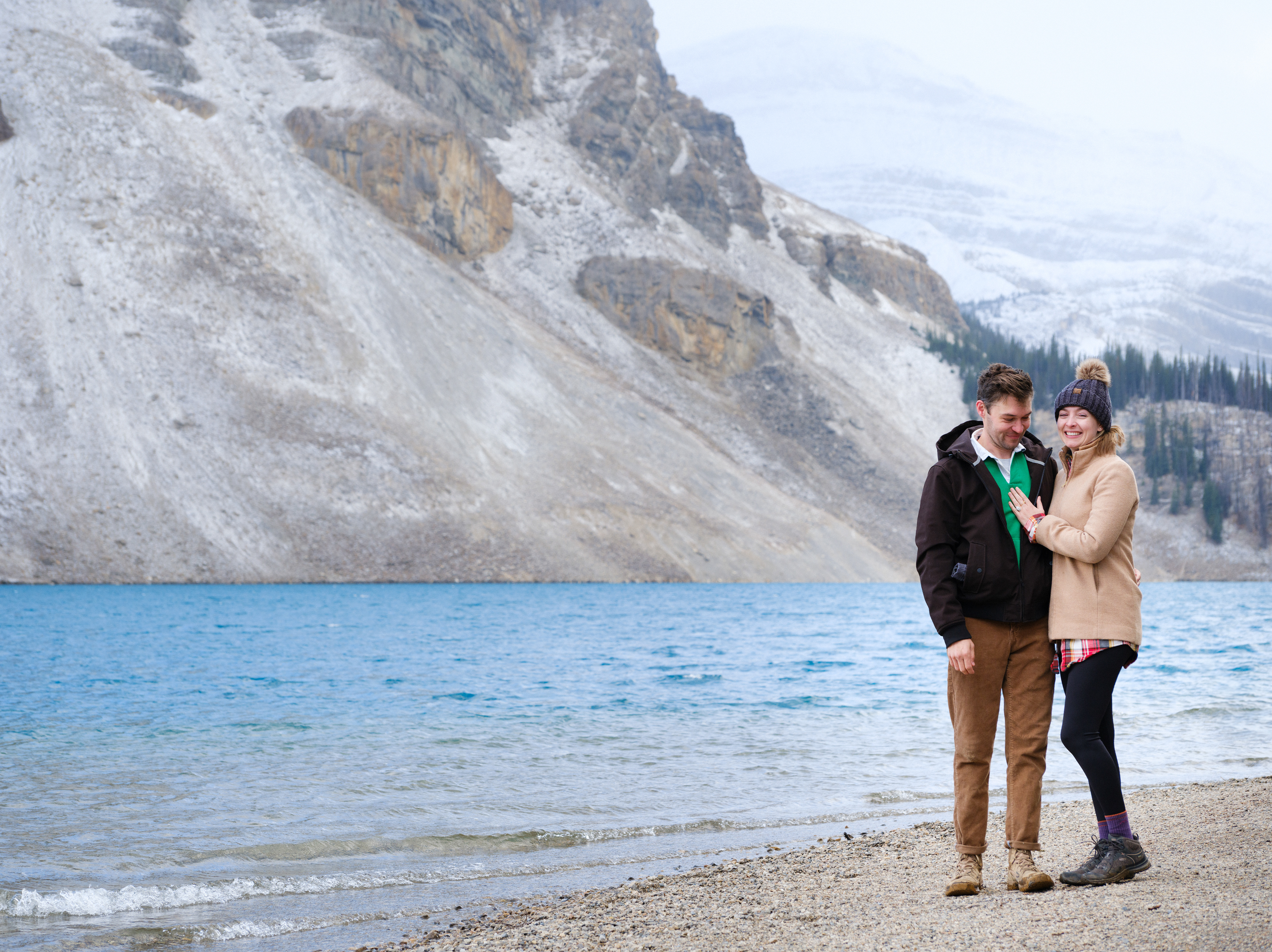 Surprise Banff proposal shoot and the couple is overjoyed and displaying the engagement ring in front of a beautiful lake.