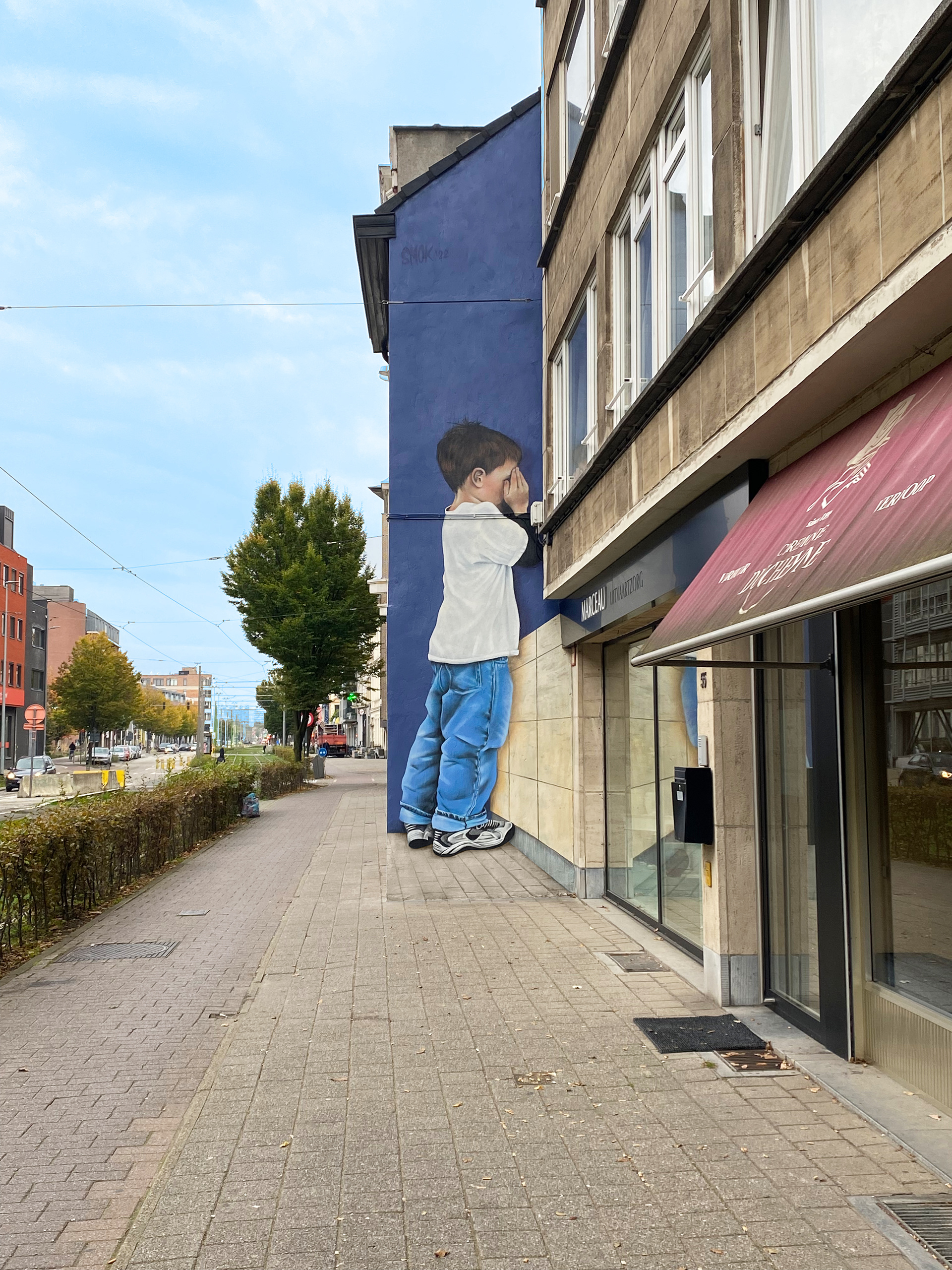 An anamorphic wallpainting by SMOK of a boy staning in the corner