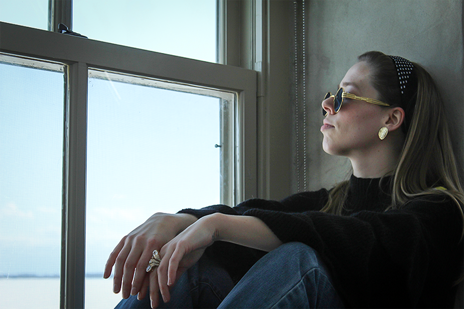Picture of a girl staring outside, sitting on a window sill