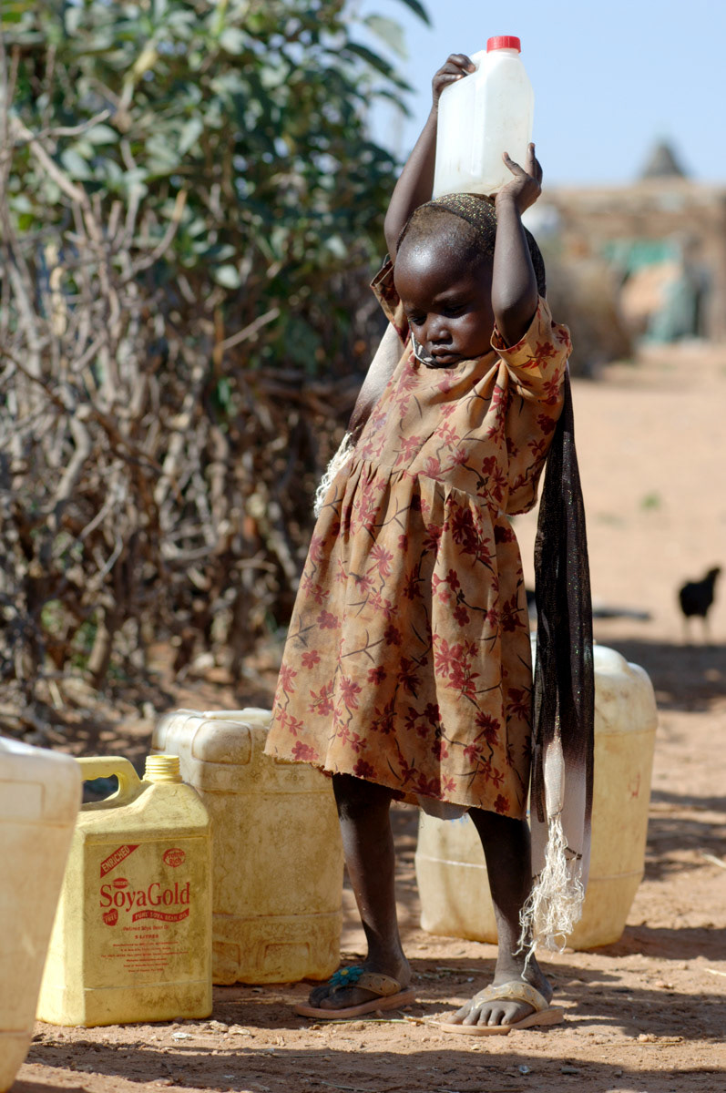 A young child tries to carry a water gerrican in an IDP camp in West Darfur, Sudan.