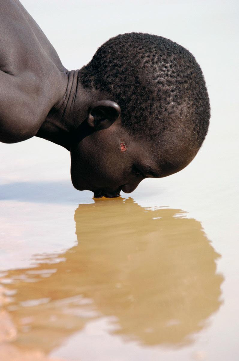 A Southern Sudanese boy drinks water from the Aquem river, north of Bahr er Gazal.