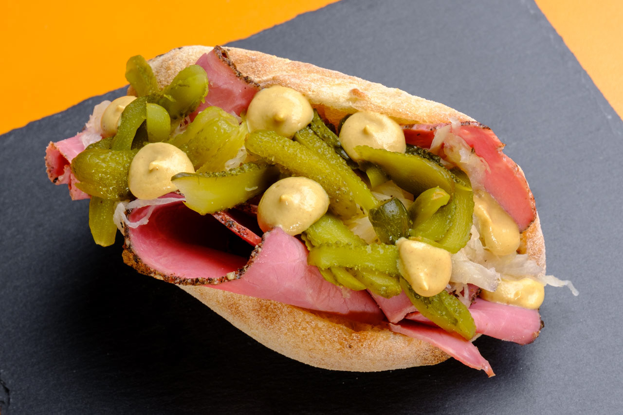 Panino croccante con cetriolini sott'aceto, cipolla, pastrami e senape