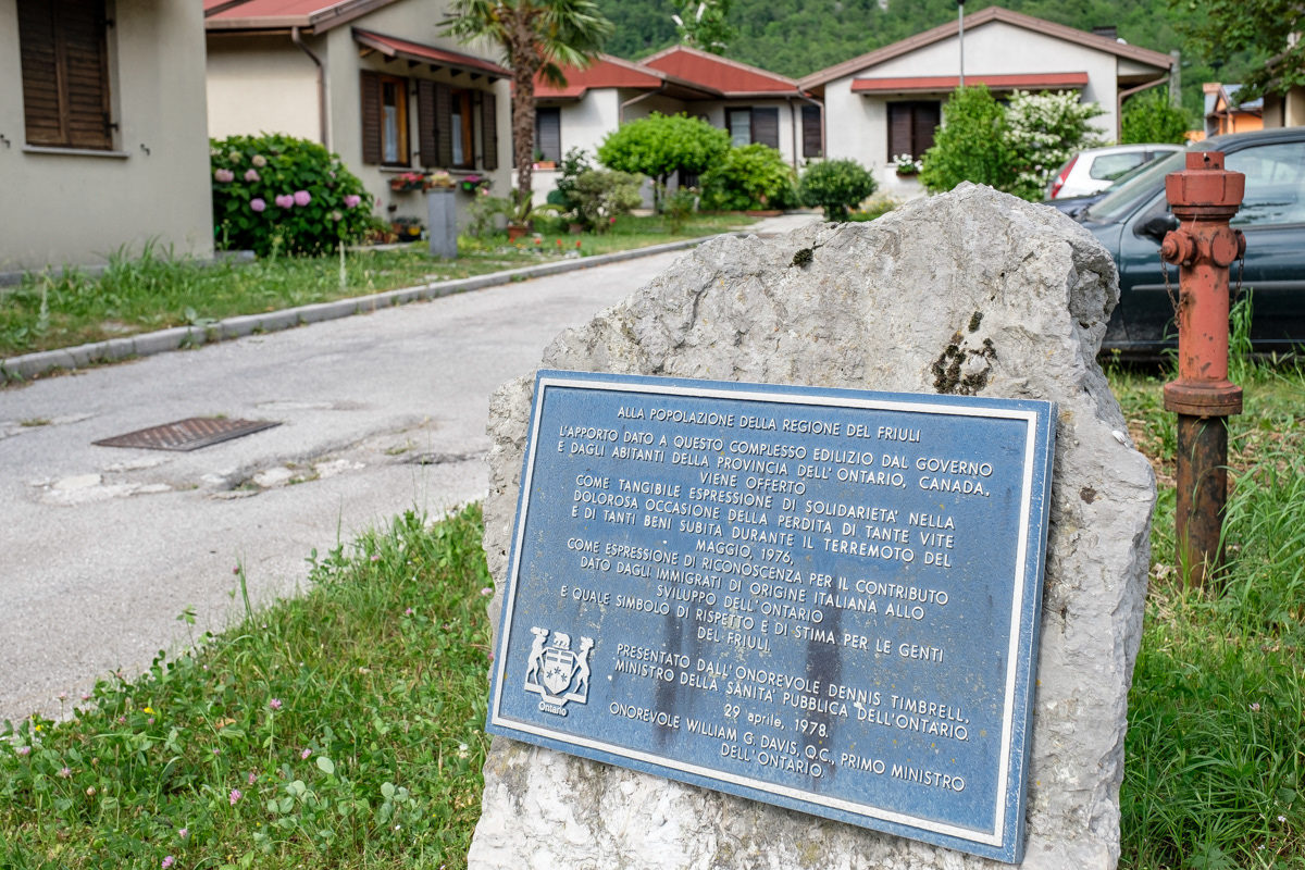 Il “villaggio Canadese” fuori le mura di Venzone; la targa ricorda la donazione del complesso edilizio da parte del governo e dei cittadini canadesi. Le case, originariamente in legno, furono poi “rivestite” di una struttura cementizia per renderle definitive e durevoli.
