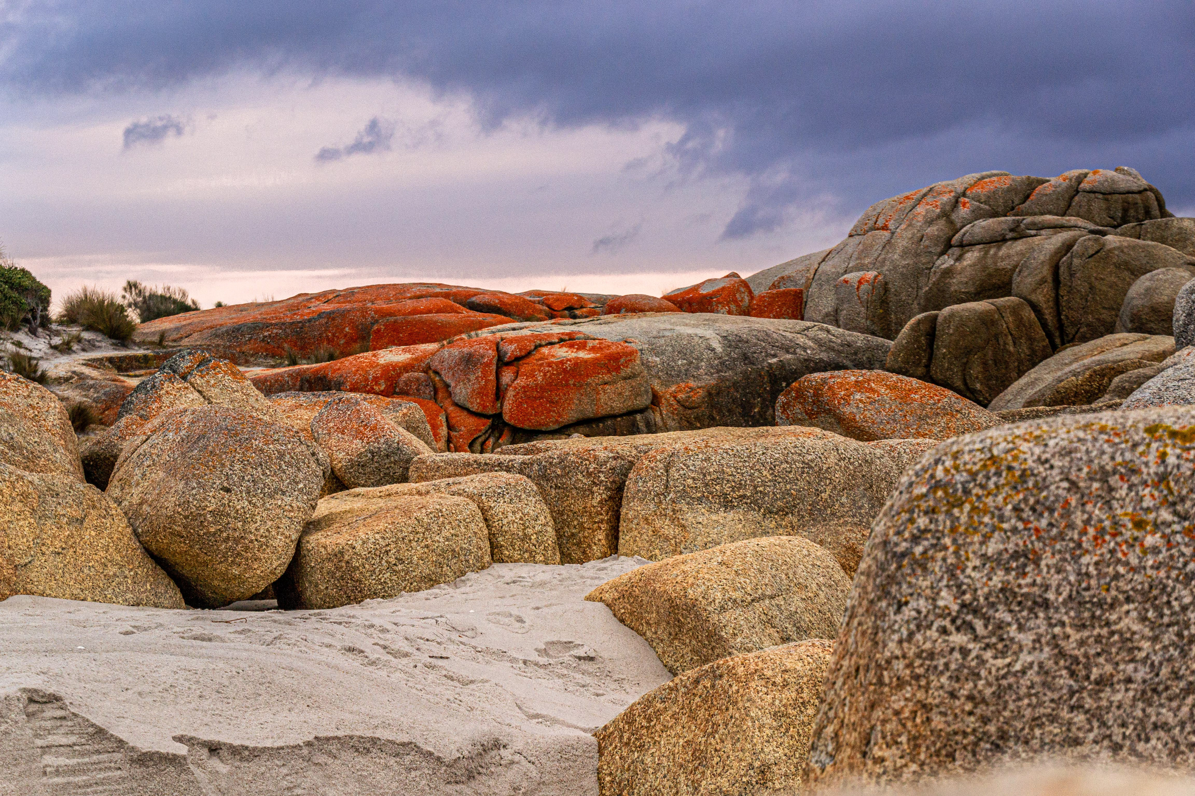 Firey capped granite boulders contrast the moody grey clouds above.