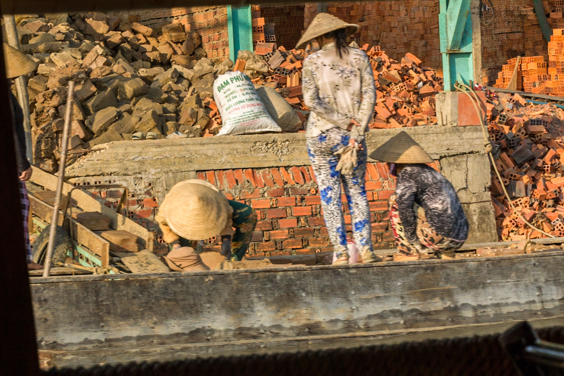 Women unloading billets of clay at the brickworks.