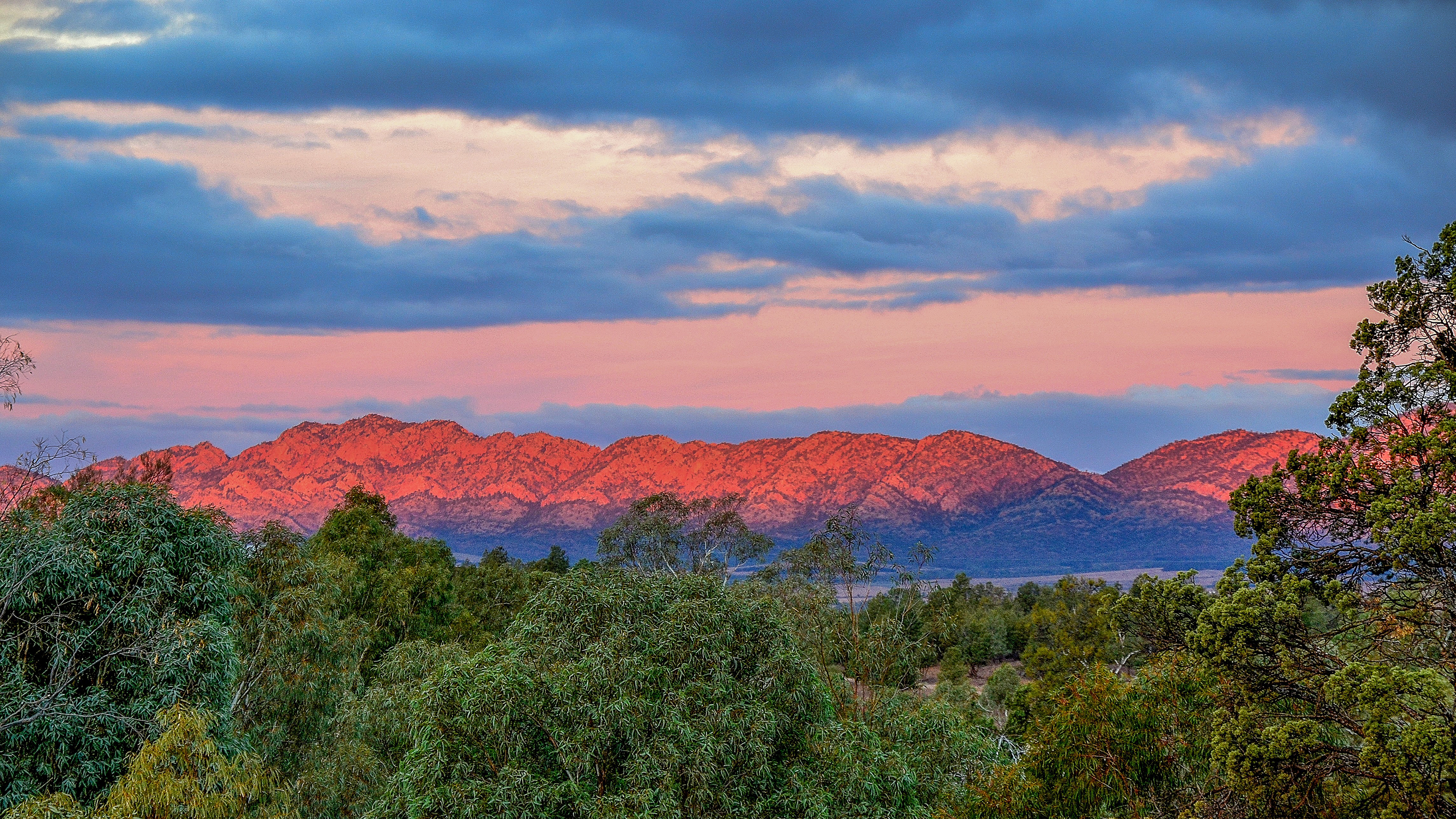 Sunset paints the distant ranges in a soft pink hue.