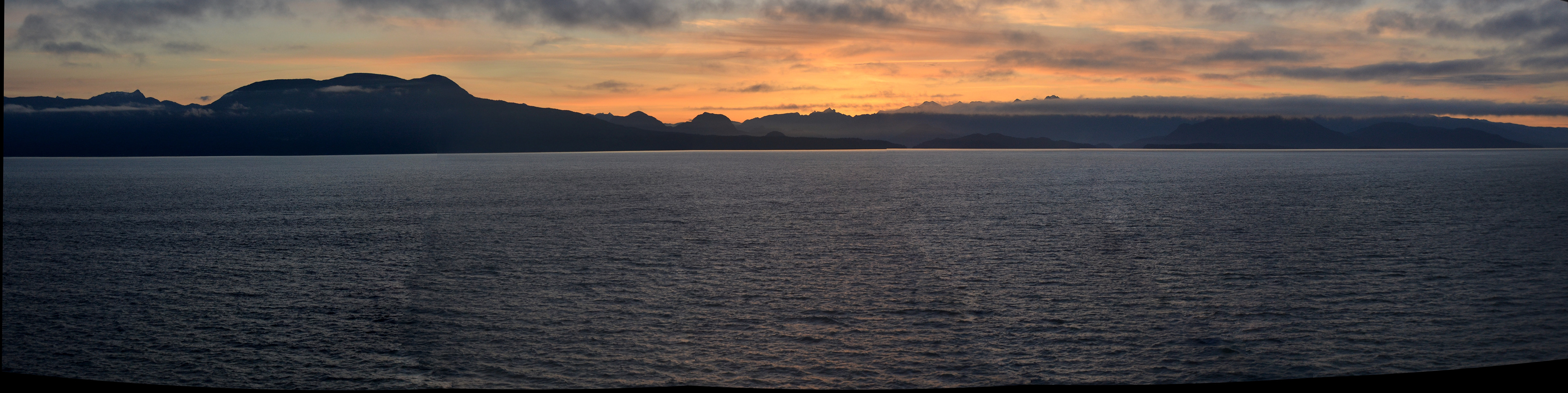The gold and magenta hues of twilight emerge as the sun recedes below Glacier Bay Basin.