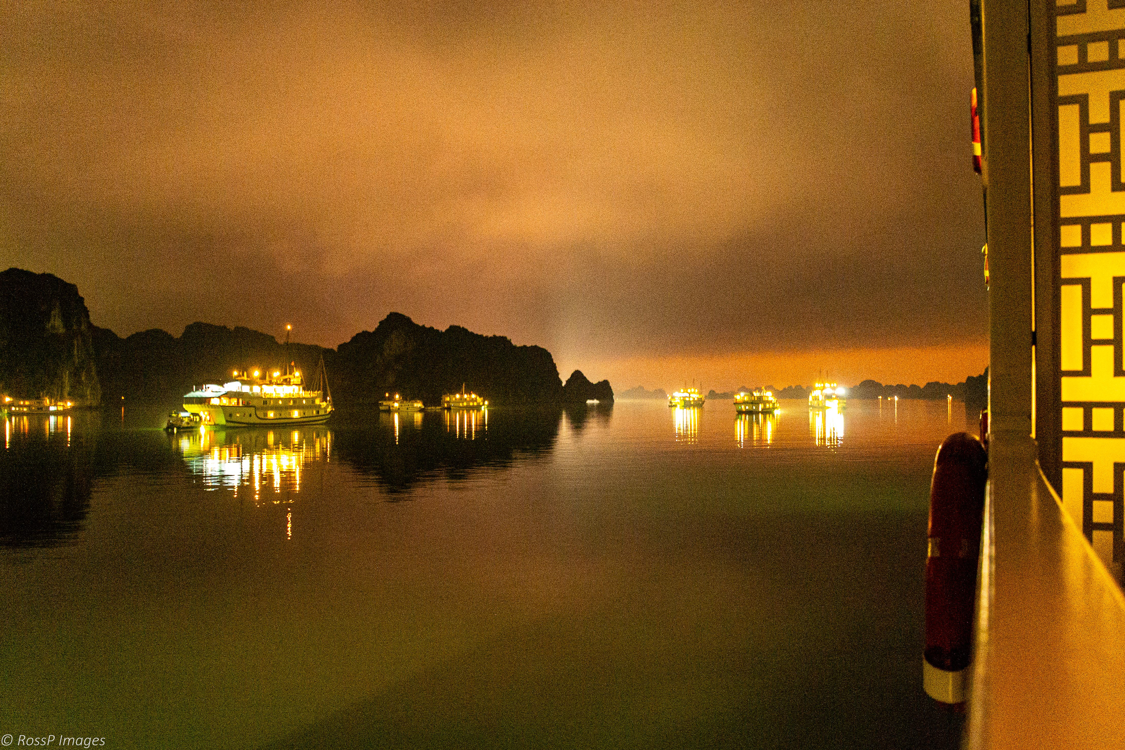 Cruise boats at anchor as an eerie night fog descends.