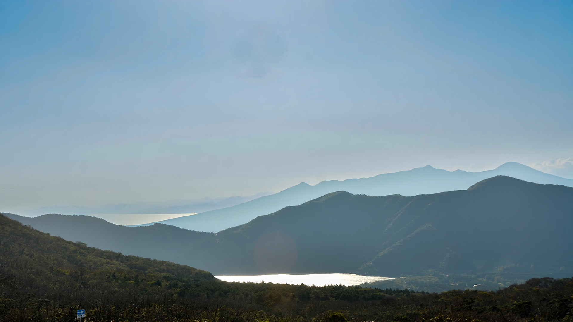 Lakes perched in the valleys below Owakudani geothermal area reflect the afternoon sunlight.
