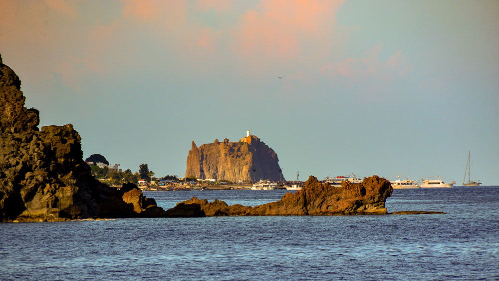 Stromboli harbour with Strombolicchio Lighthouse in the background. The basalt sea stack is a remnant volcano core.