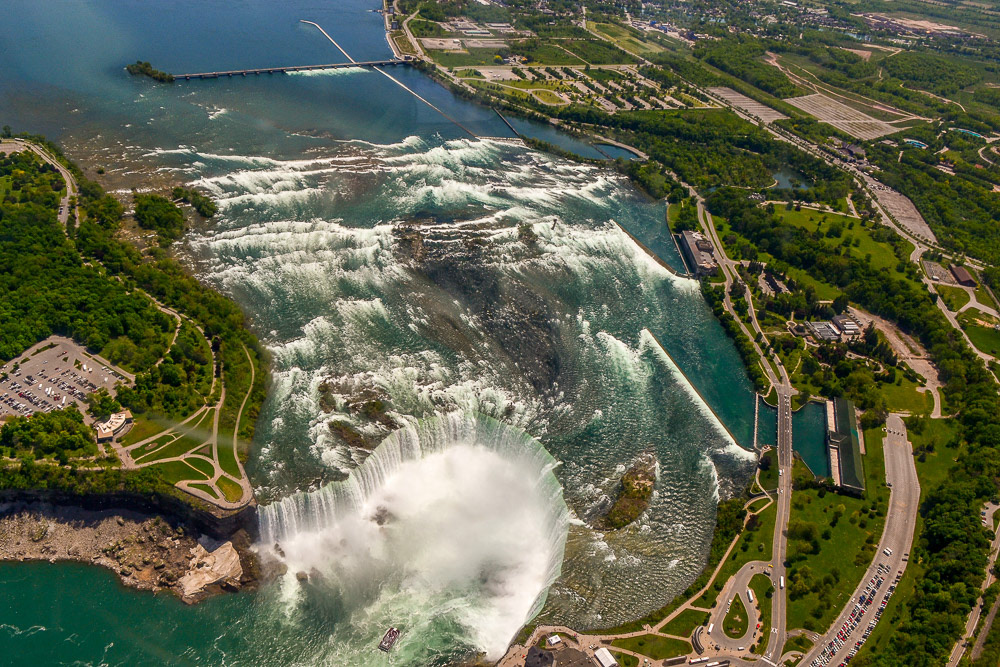 Horseshoe Falls and upstream rapids with a tourist boat mid-stream at the base of the falls.